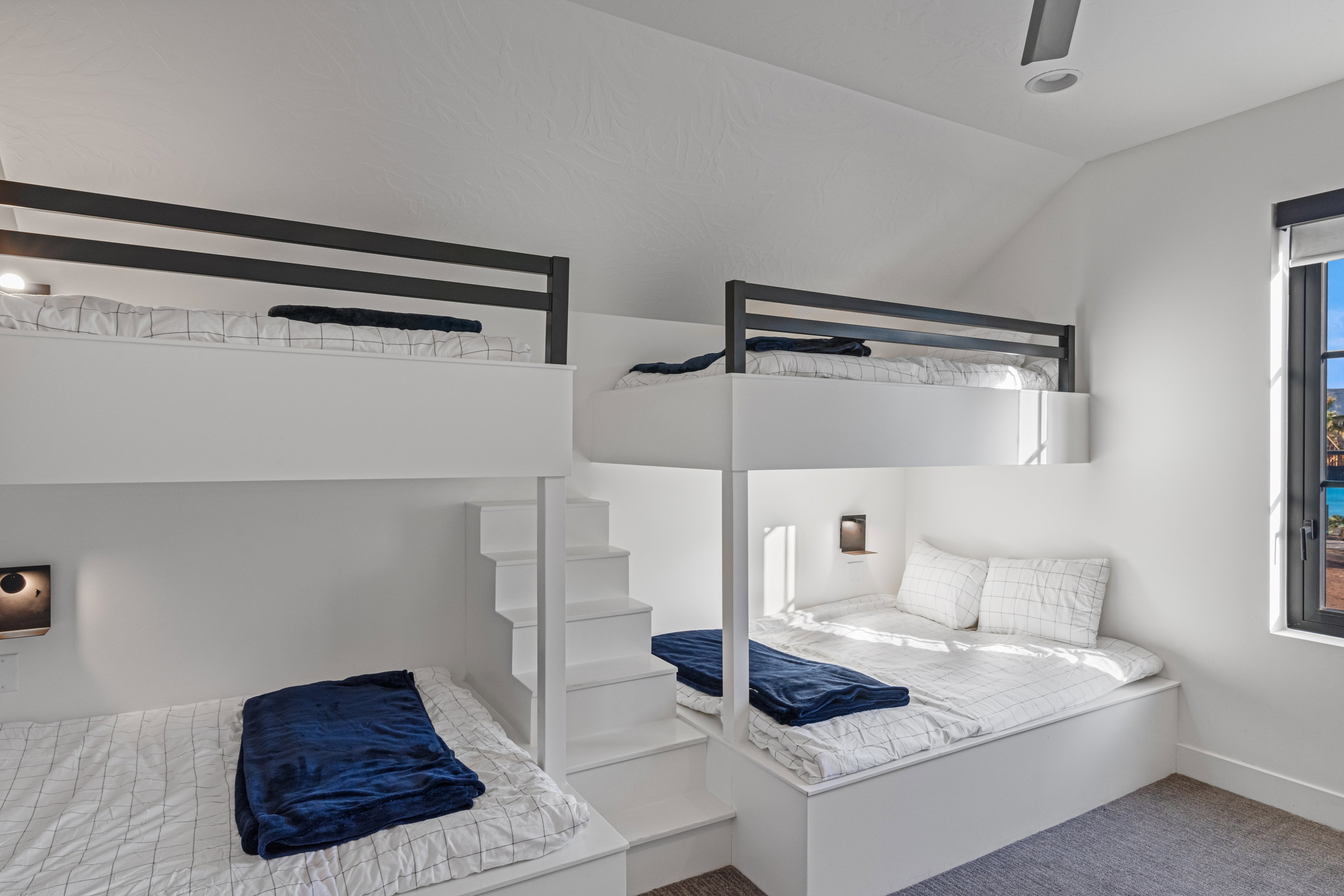 Integrated bunk beds featuring built-in stair access, individual lighting fixtures, and a vaulted ceiling