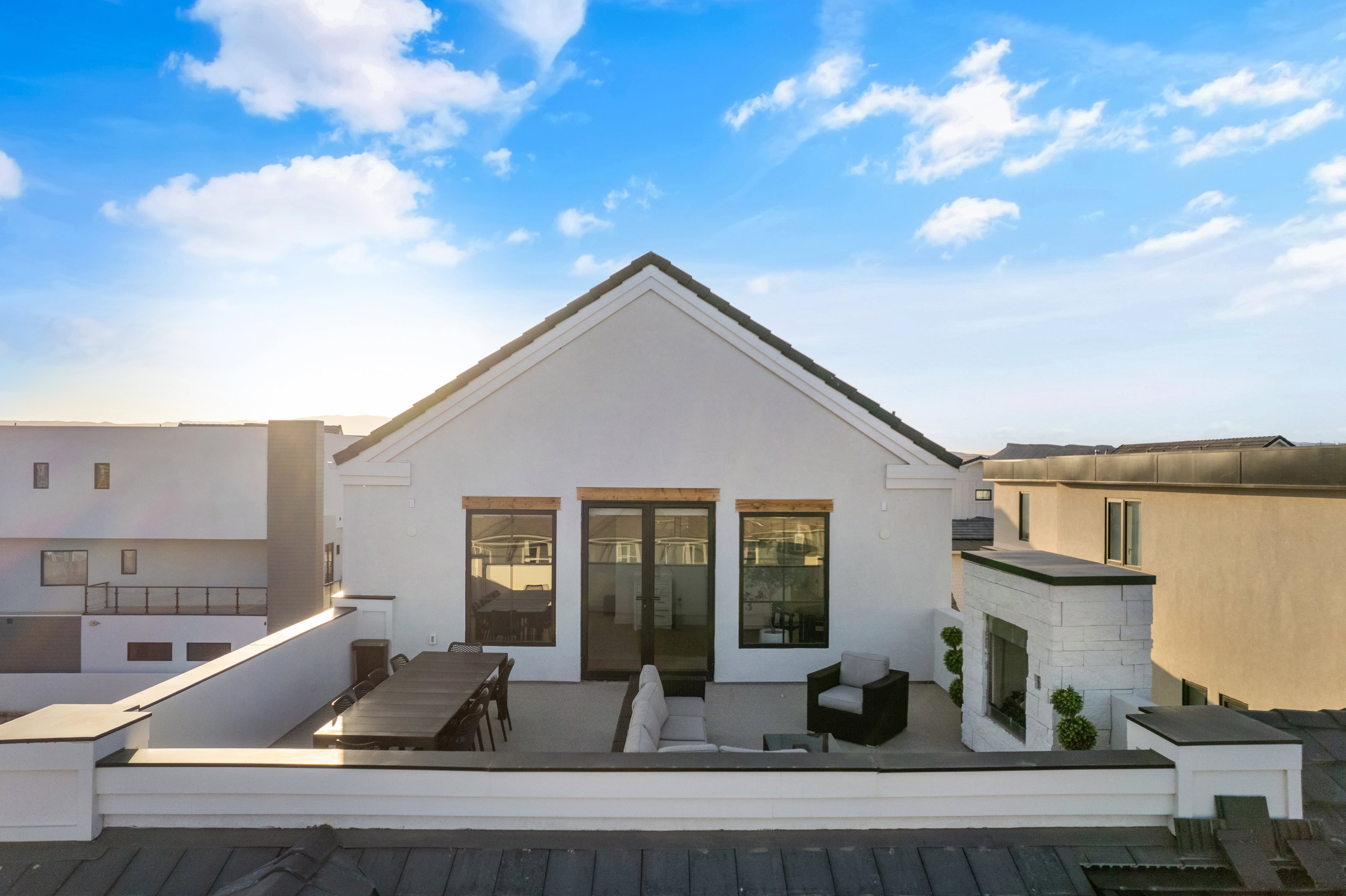 Rooftop deck featuring an outdoor fireplace, a spacious patio area, black-framed glass doors, and durable white exterior siding