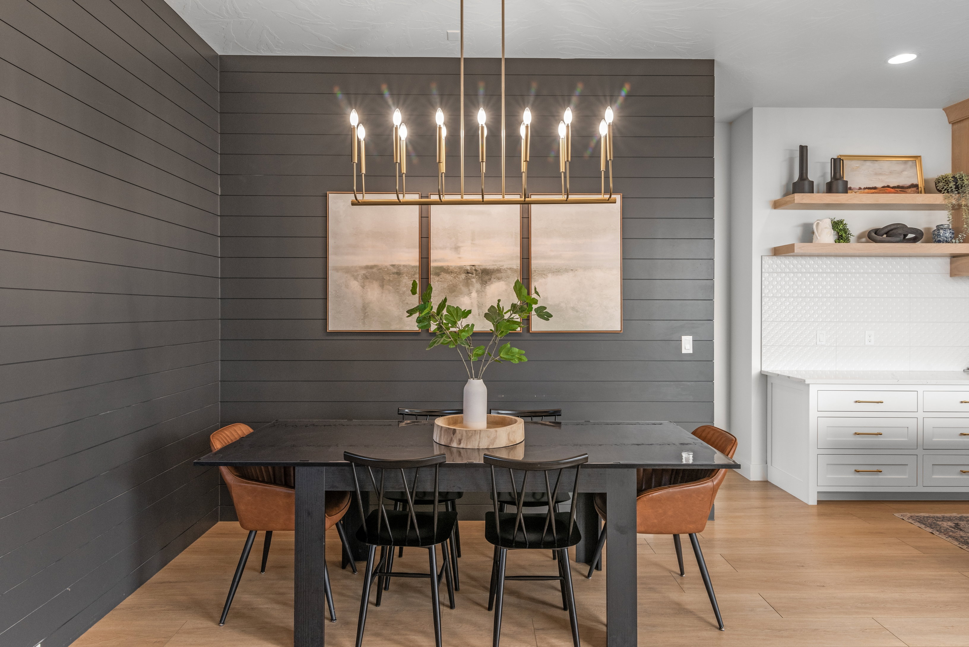 Dining area featuring a linear chandelier over a dark-toned table