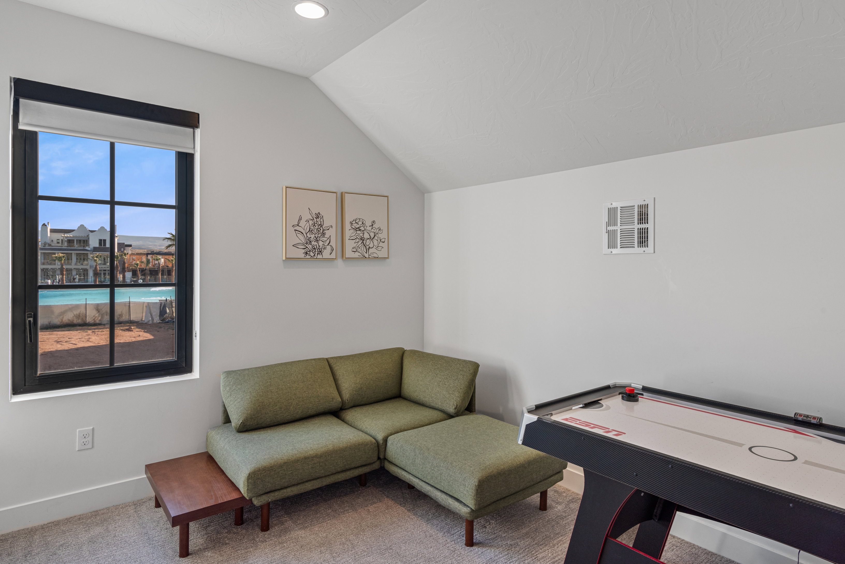 Interior room featuring a large black-framed window with grid panes, recessed lighting, and an angled ceiling line