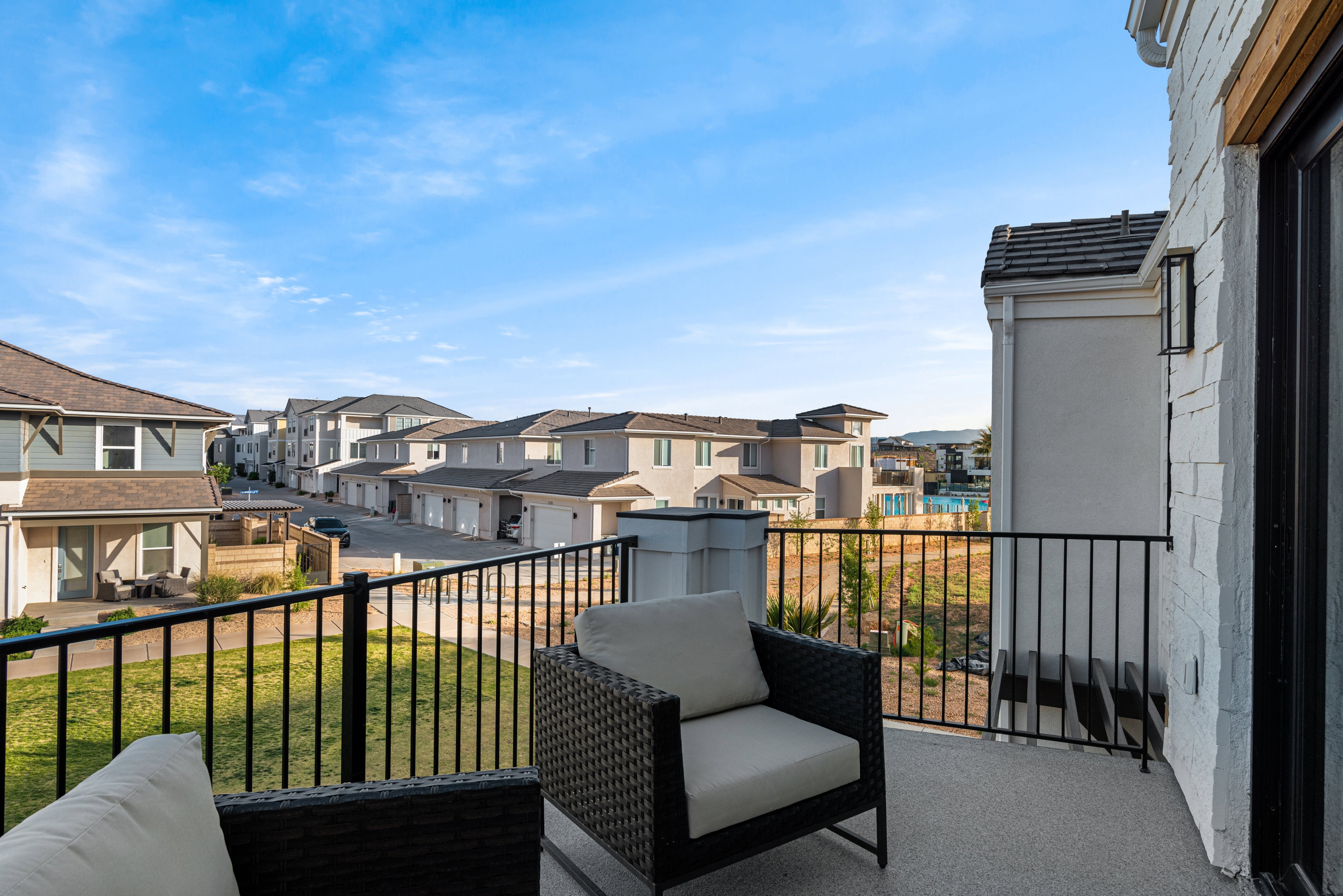 Balcony space featuring a textured concrete surface, black metal railings, and an exterior wall with white stacked stone detailing