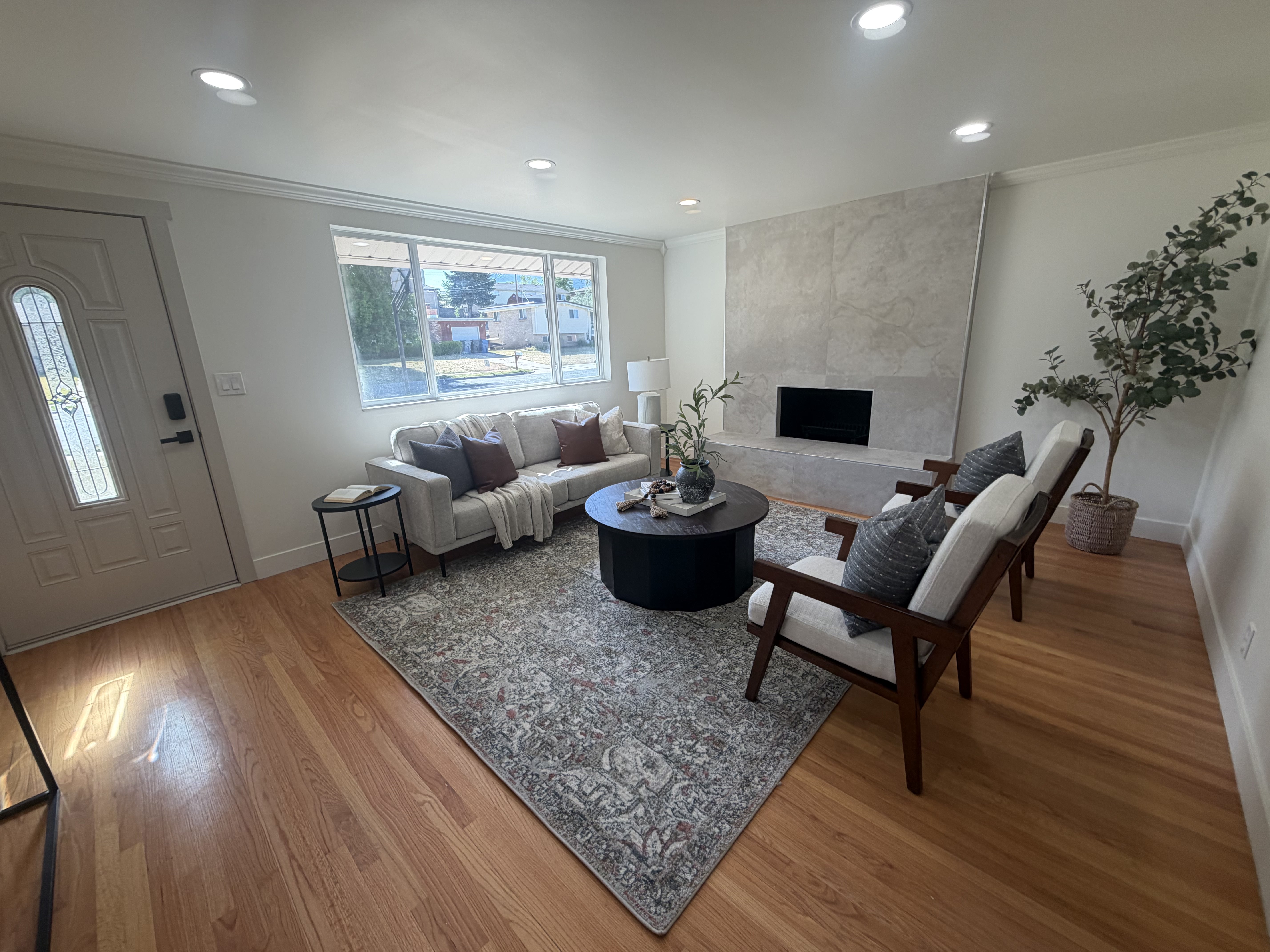 Living area featuring a modern fireplace with a light-toned stone surround, recessed lighting, and wood-finish flooring