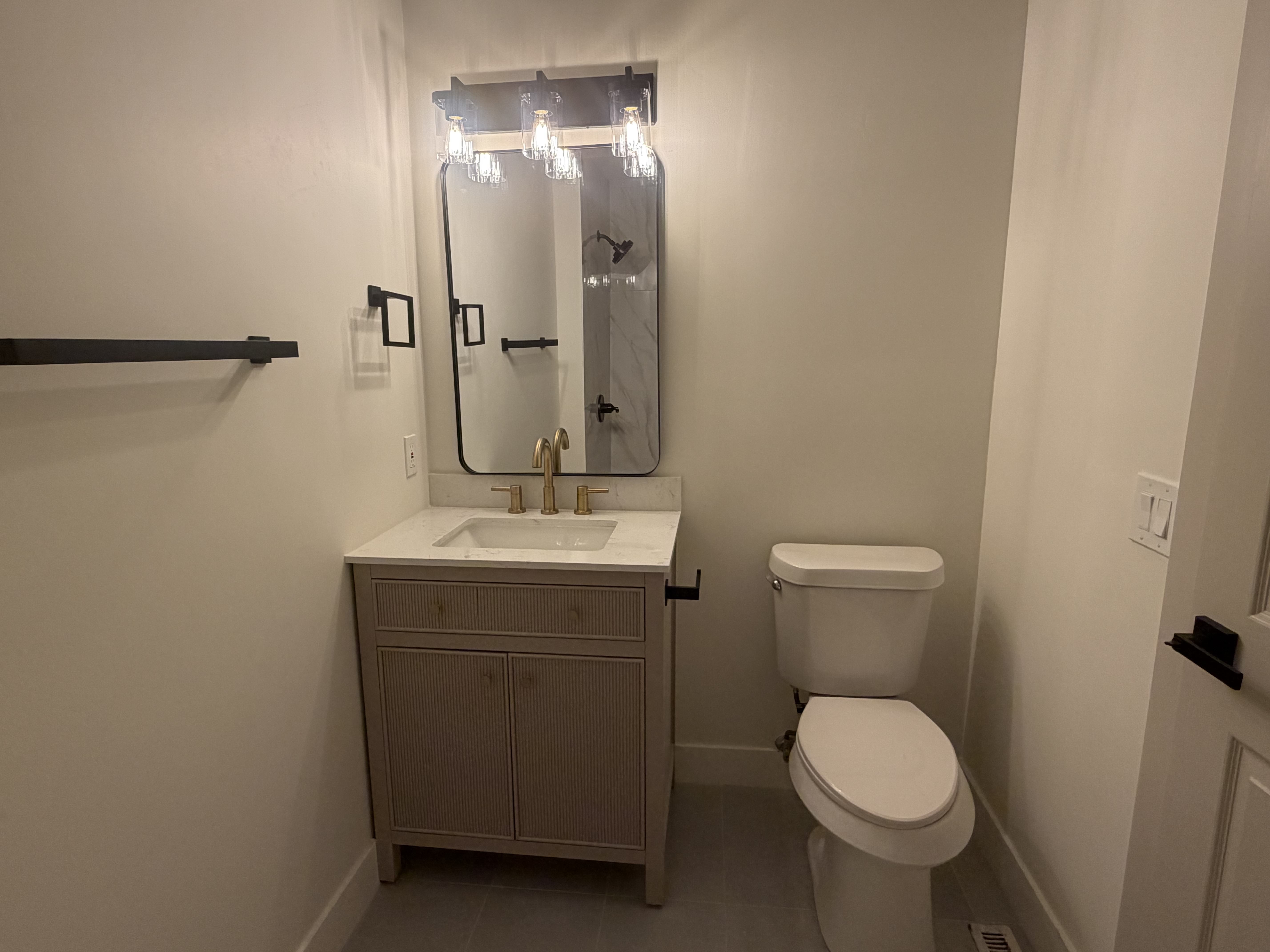 Main level, full bathroom. Bathroom vanity featuring a rectangular undermount sink, brass-finish faucet, and a light-toned countertop
