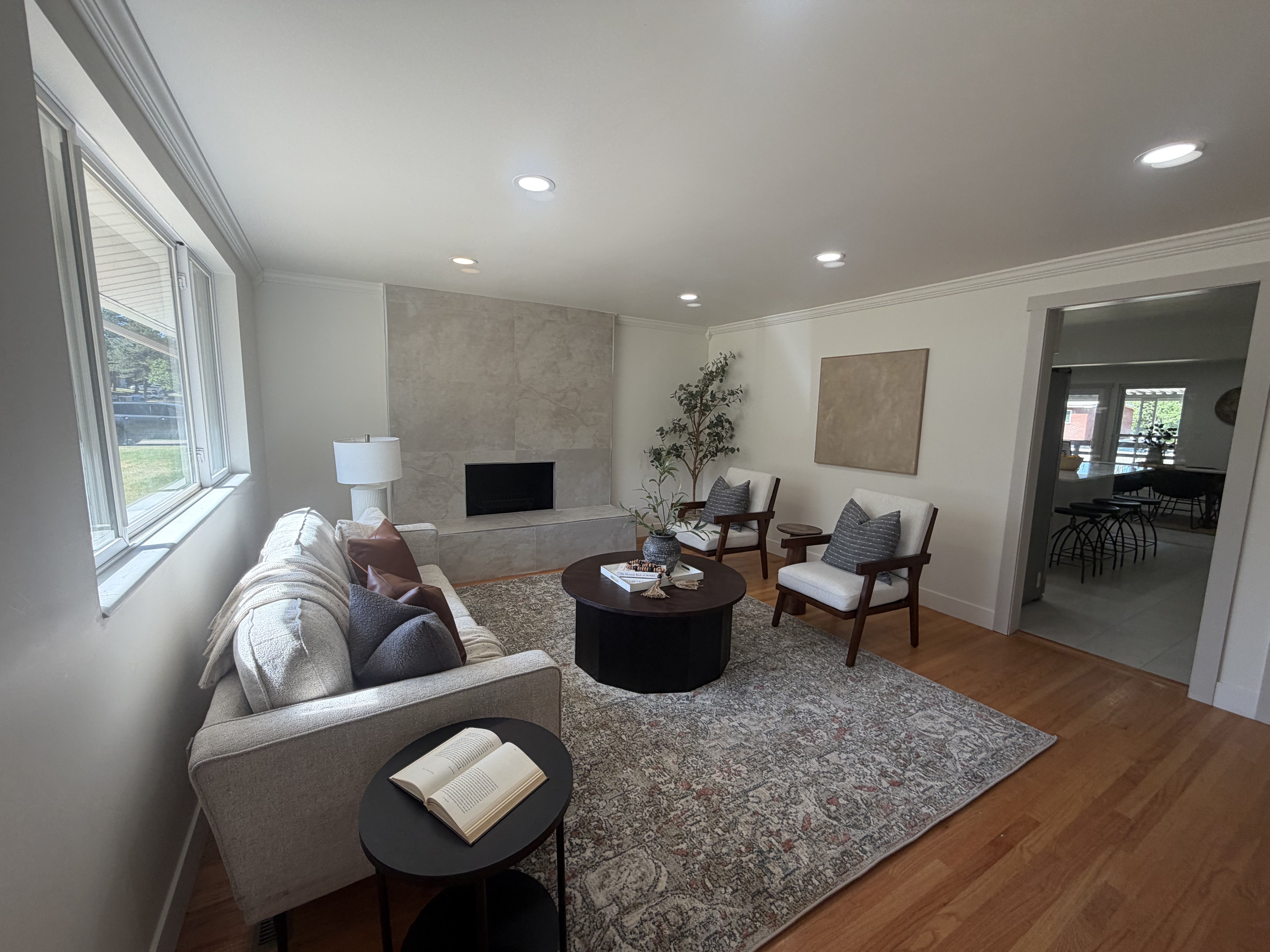 Living area featuring wood-finish flooring, recessed lighting, and a prominent fireplace with a stone-finish facade