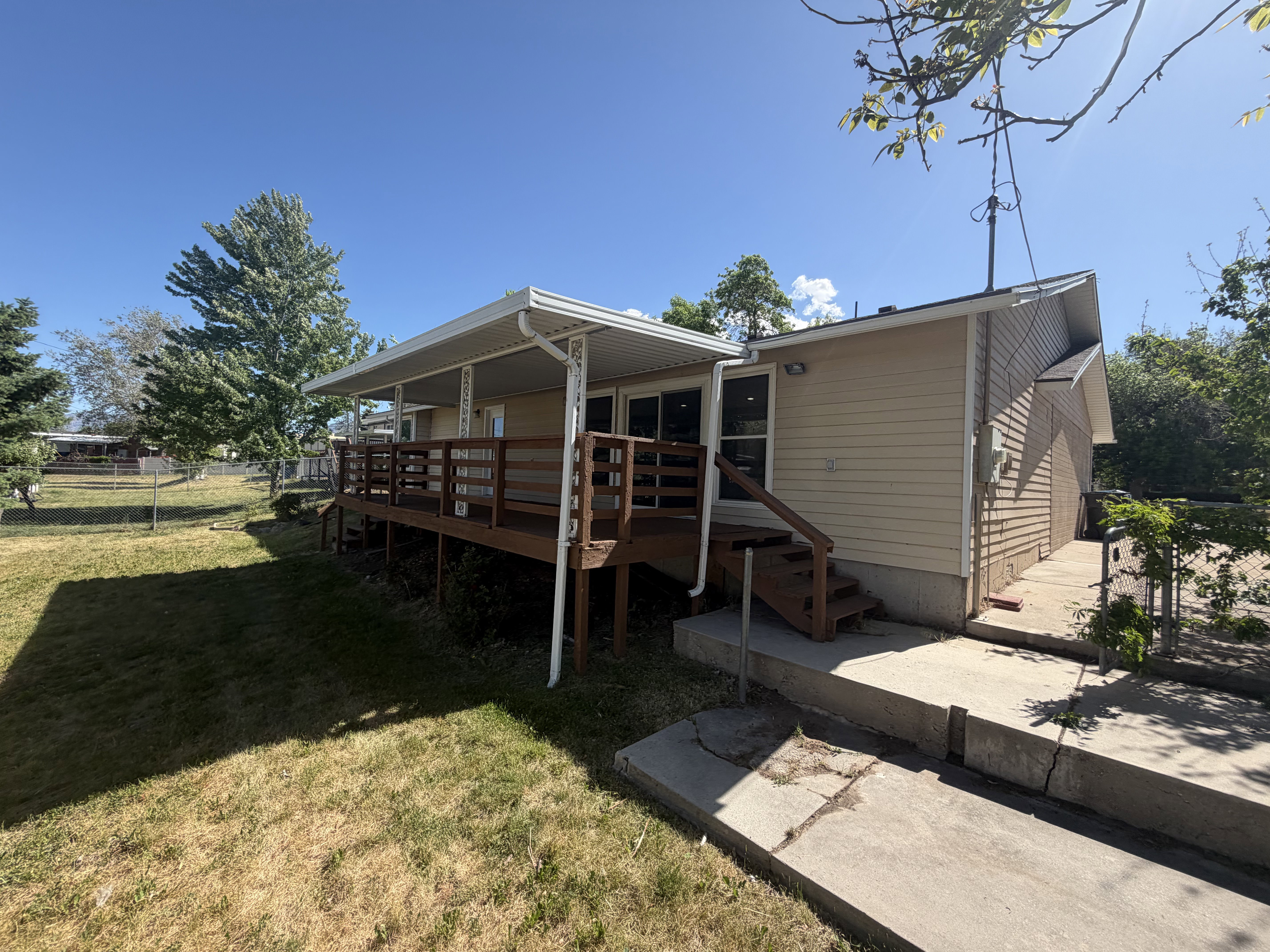 Expansive outdoor deck with a covered patio, featuring a wooden railing and steps