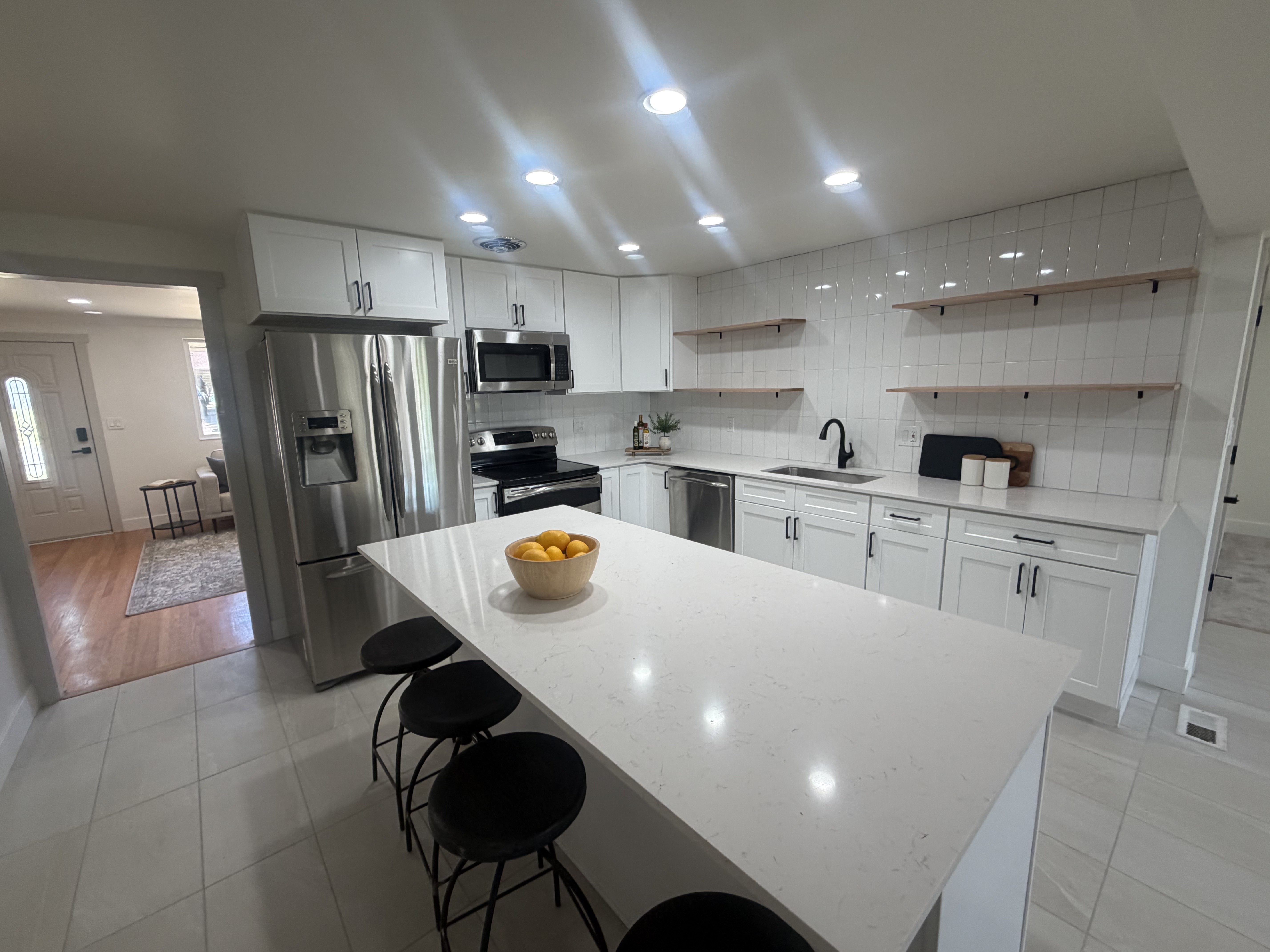 Kitchen featuring a quartz-top island, white cabinetry, stainless steel appliances, a white subway tile backsplash, and recessed lighting