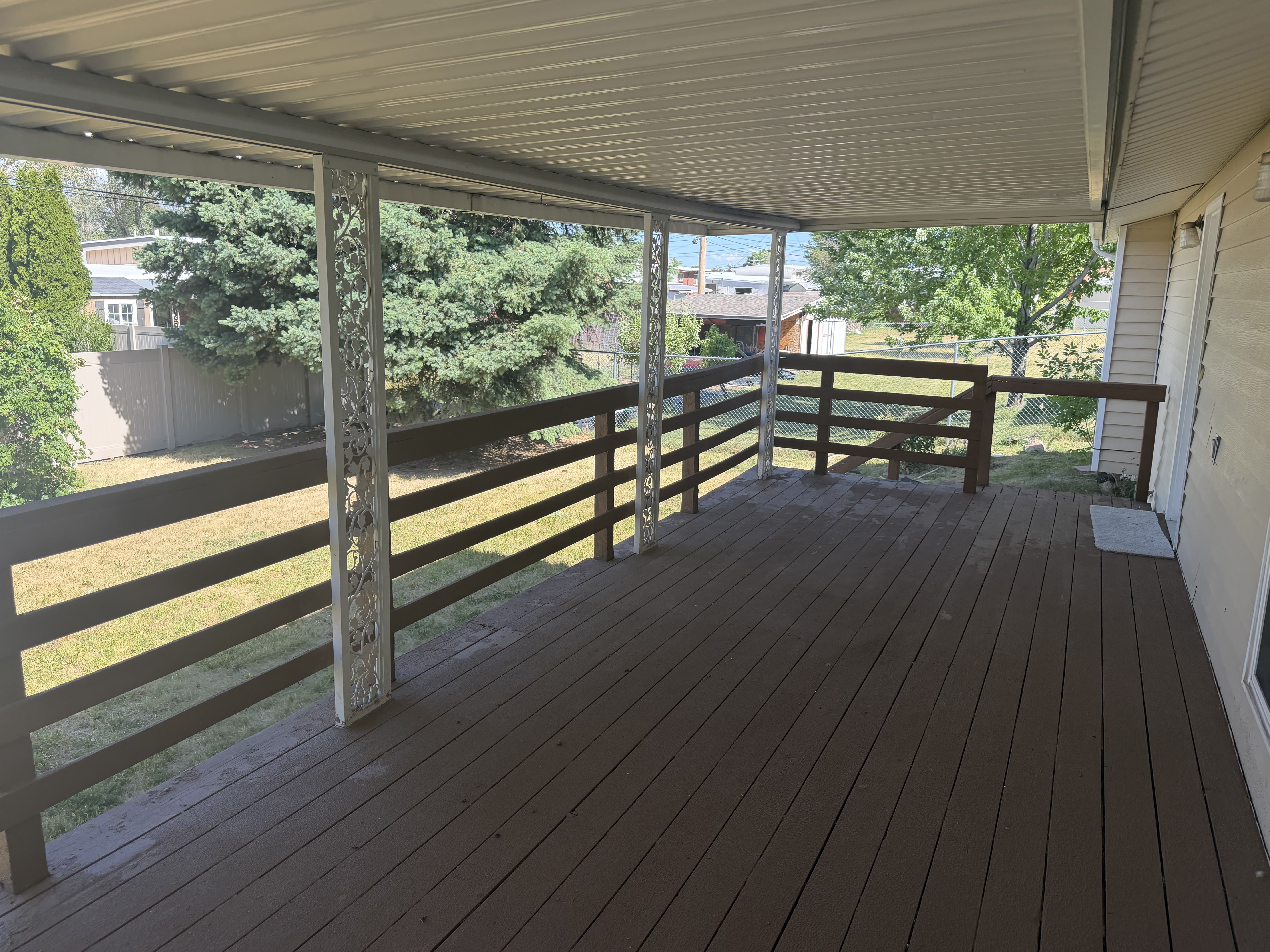 Expansive covered deck featuring wood-finish flooring and decorative metal support columns