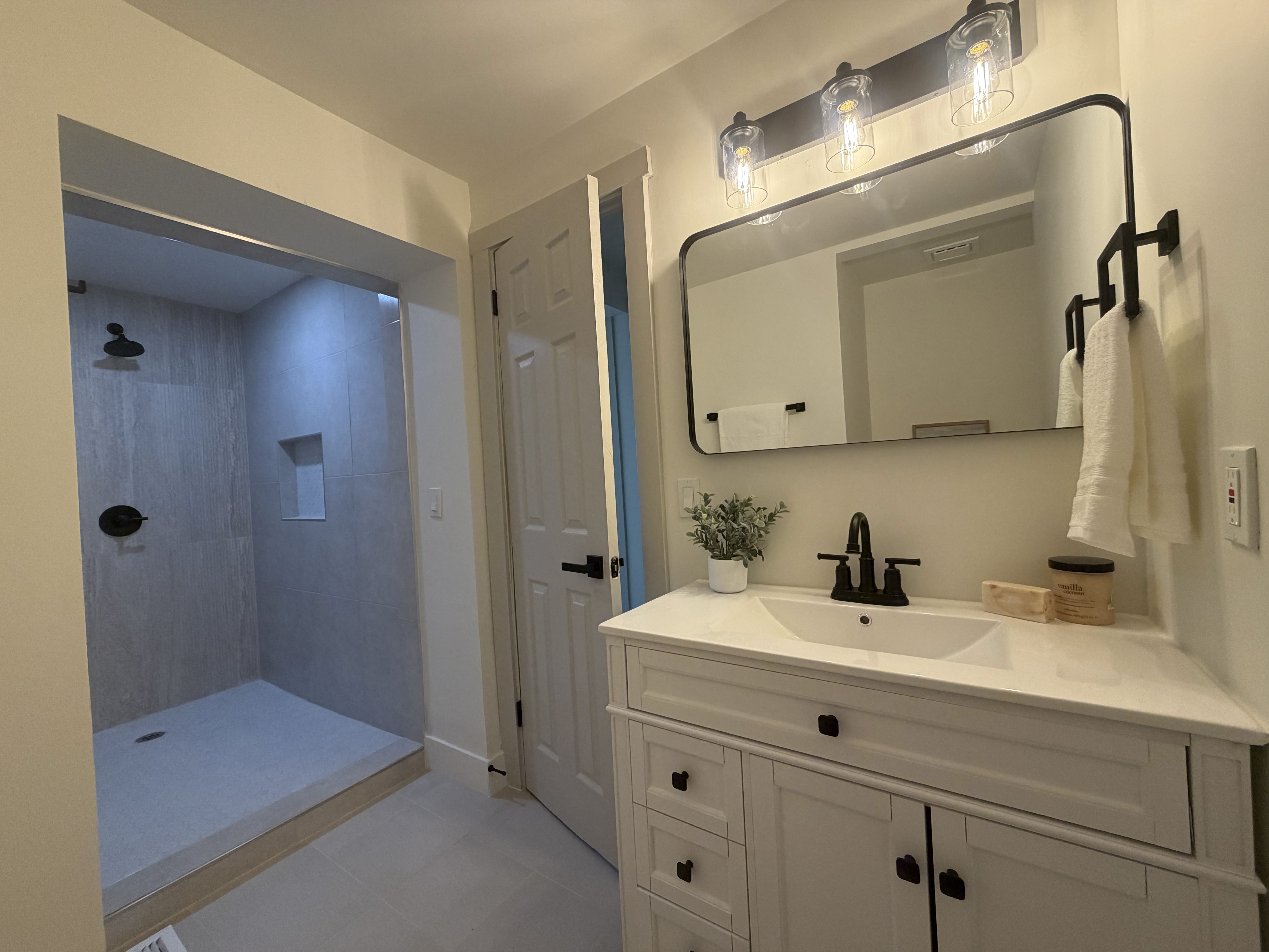 Master bathroom featuring a walk-in shower with light grey tile, a built-in shower niche, and matte black fixtures