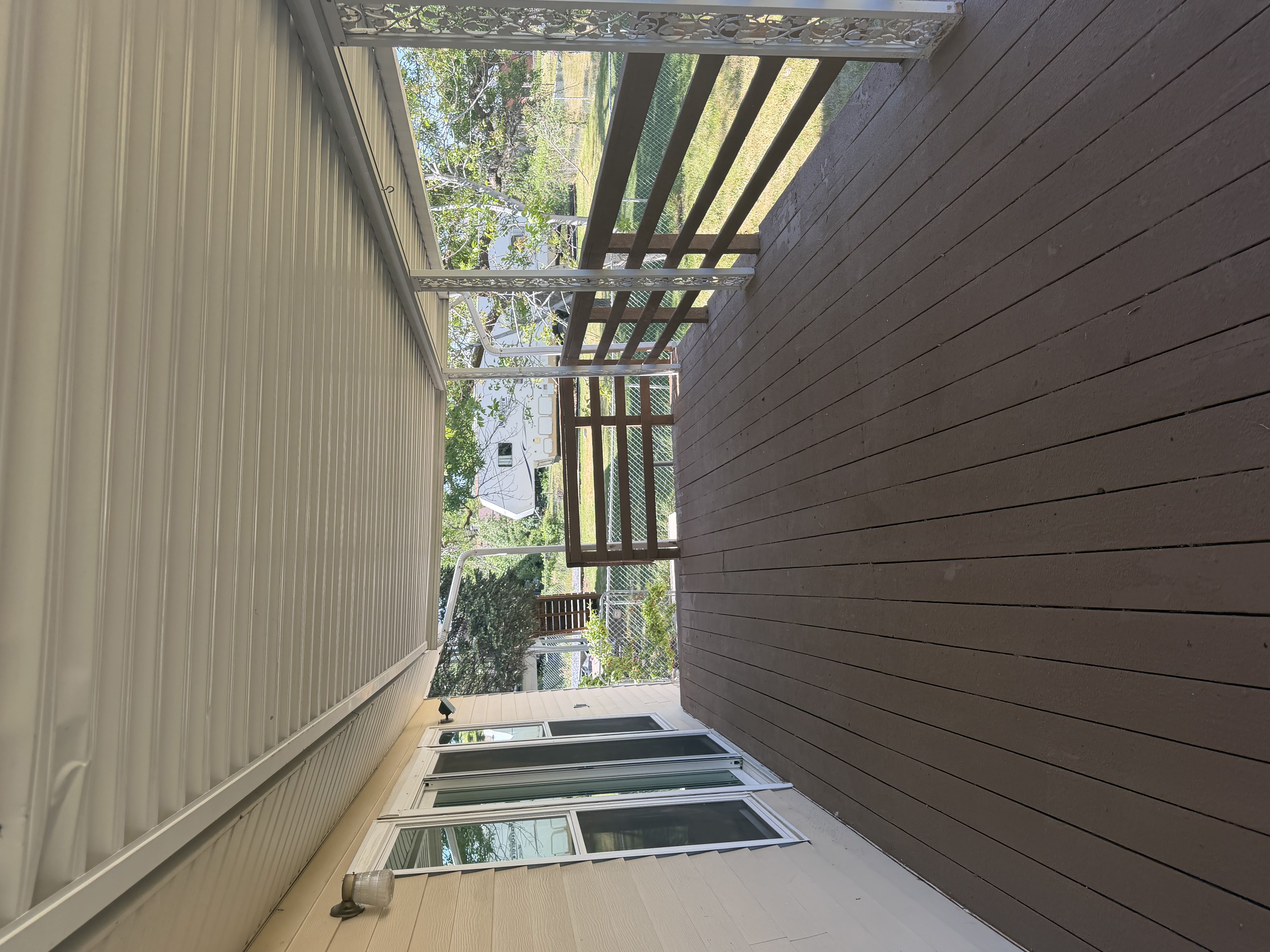 Expansive covered outdoor deck featuring wood-finish flooring, a white metal ceiling, and decorative railing elements