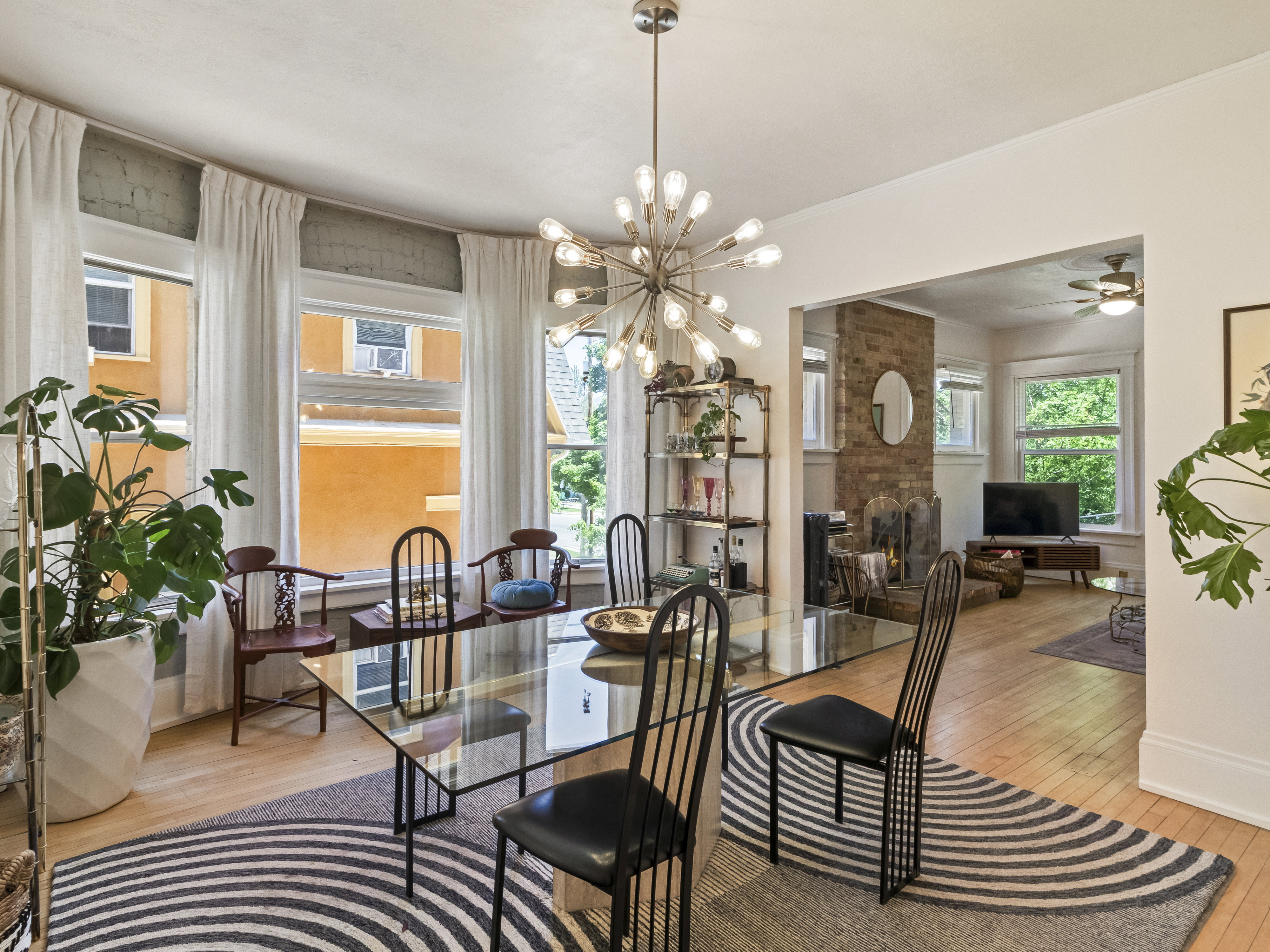 Dining space featuring hardwood flooring, a contemporary chandelier, and a curved wall of multiple windows
