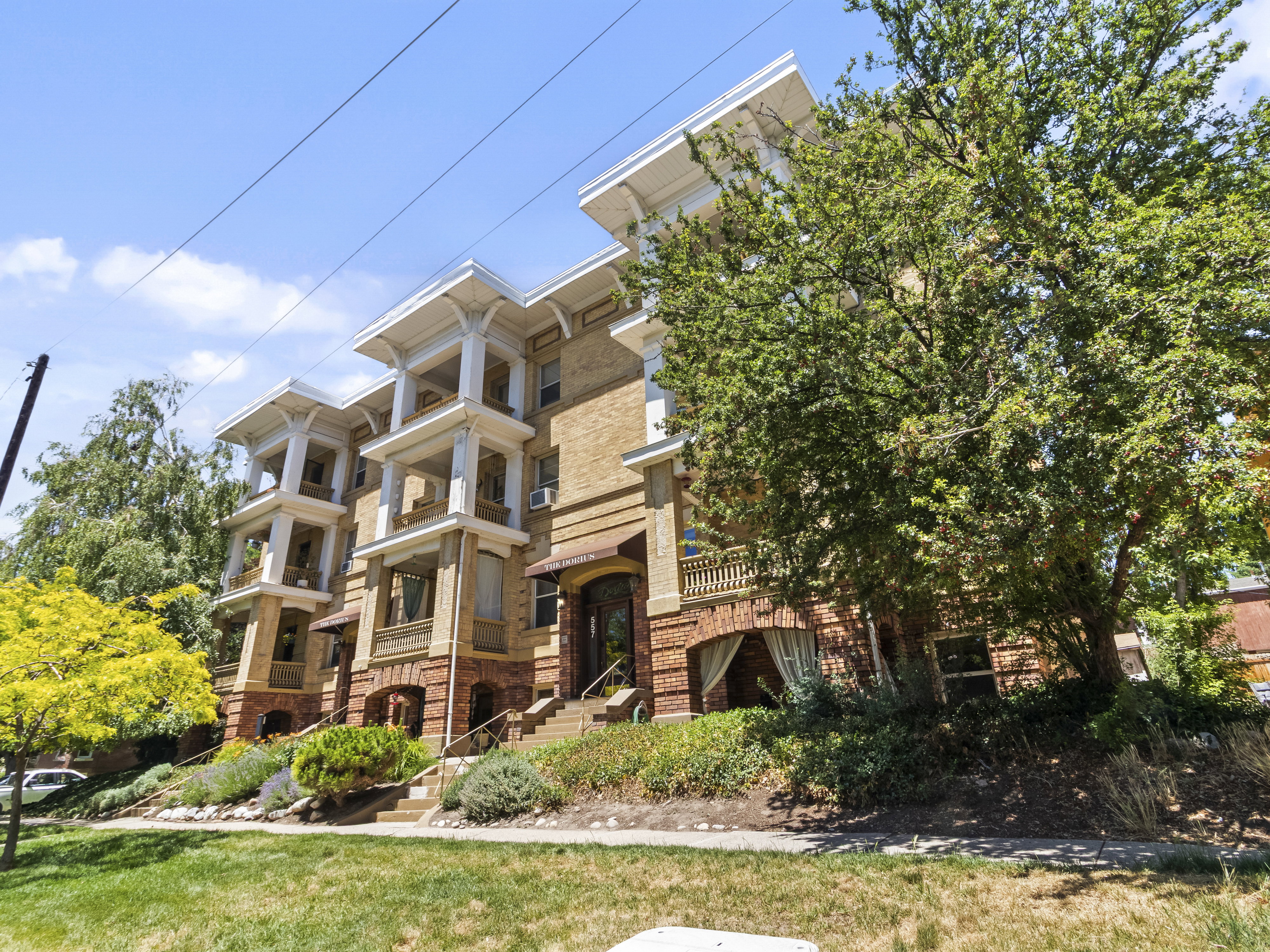 Brick building with multi-level balconies featuring intricate white columns and detailed trim