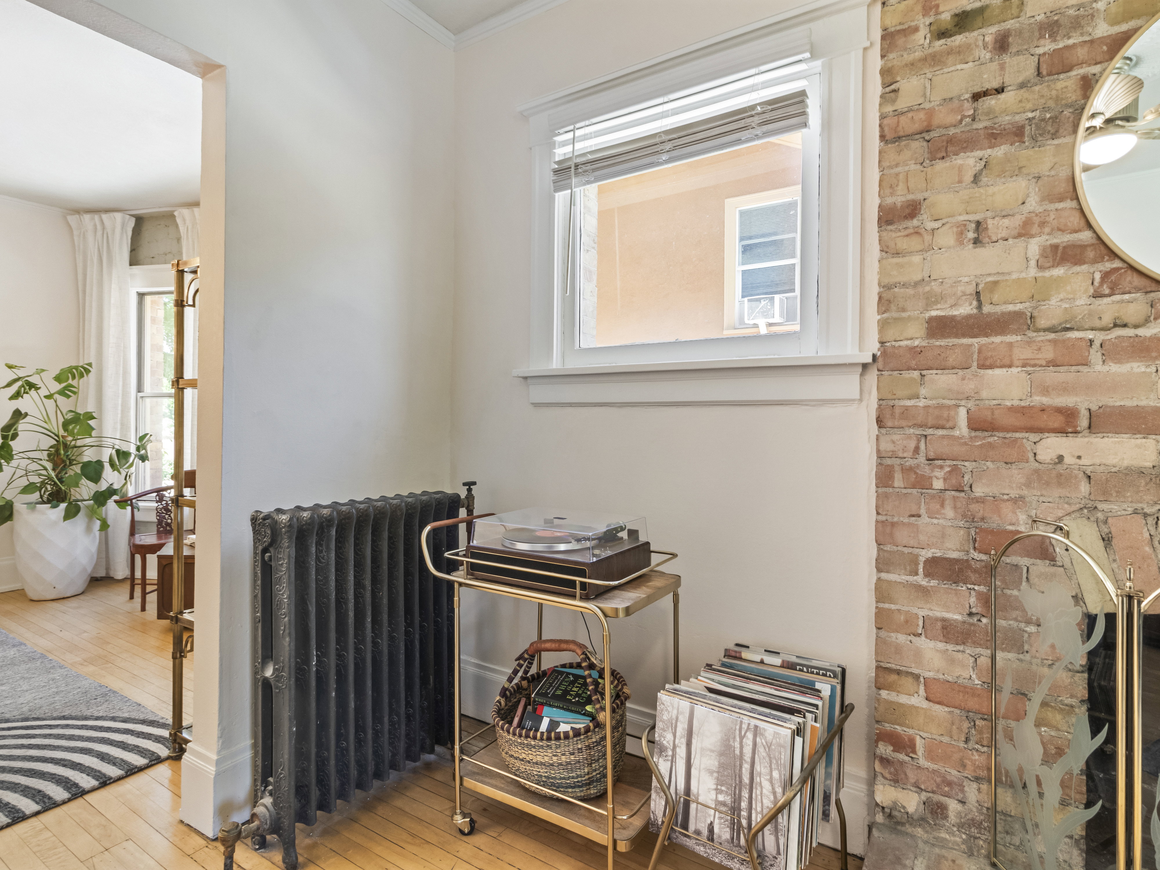 Exposed brick wall feature with a white window frame and a cast iron radiator