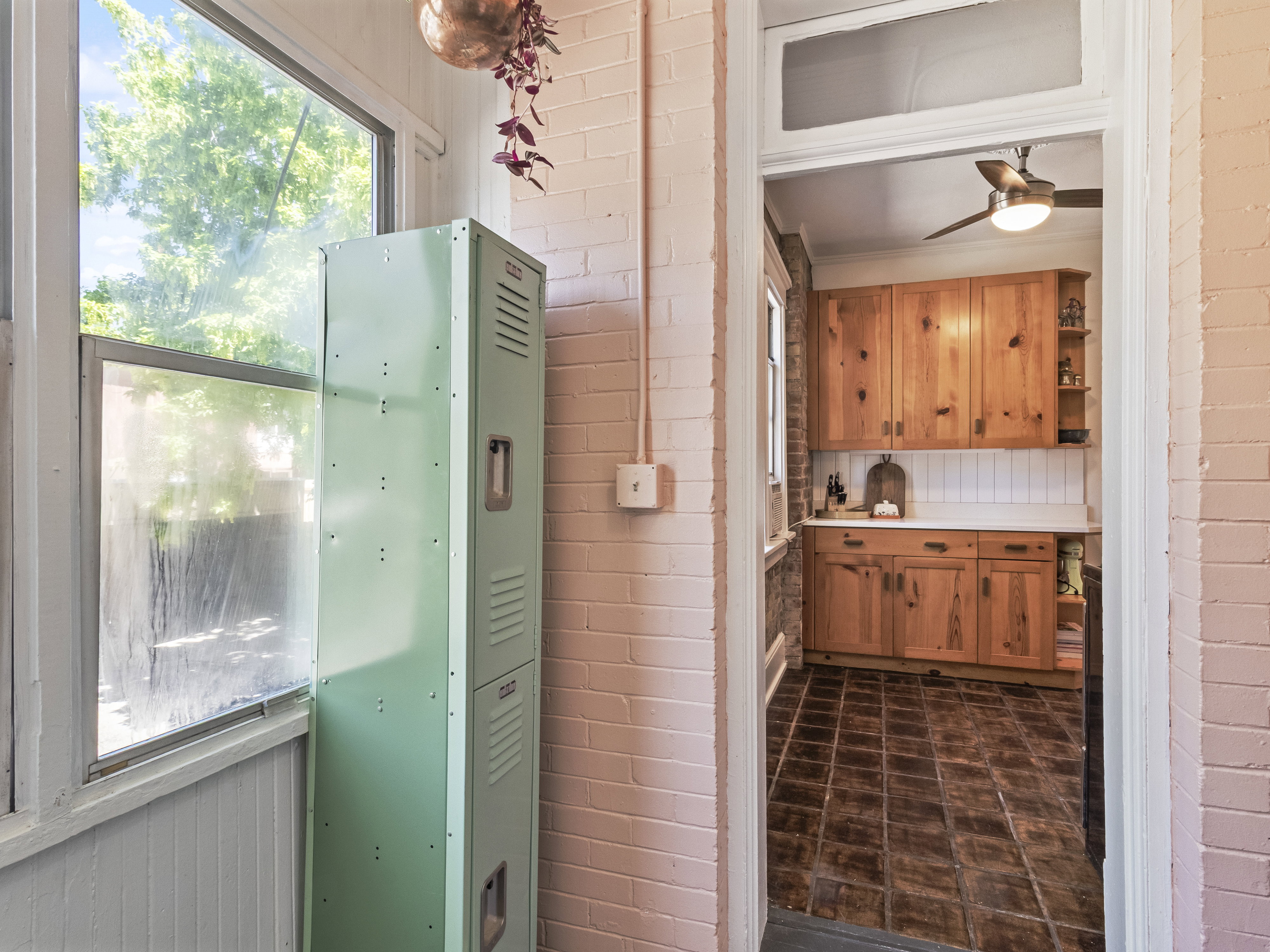 Archway opening to a kitchen featuring warm-toned wood cabinetry, white countertops, and a subway tile backsplash