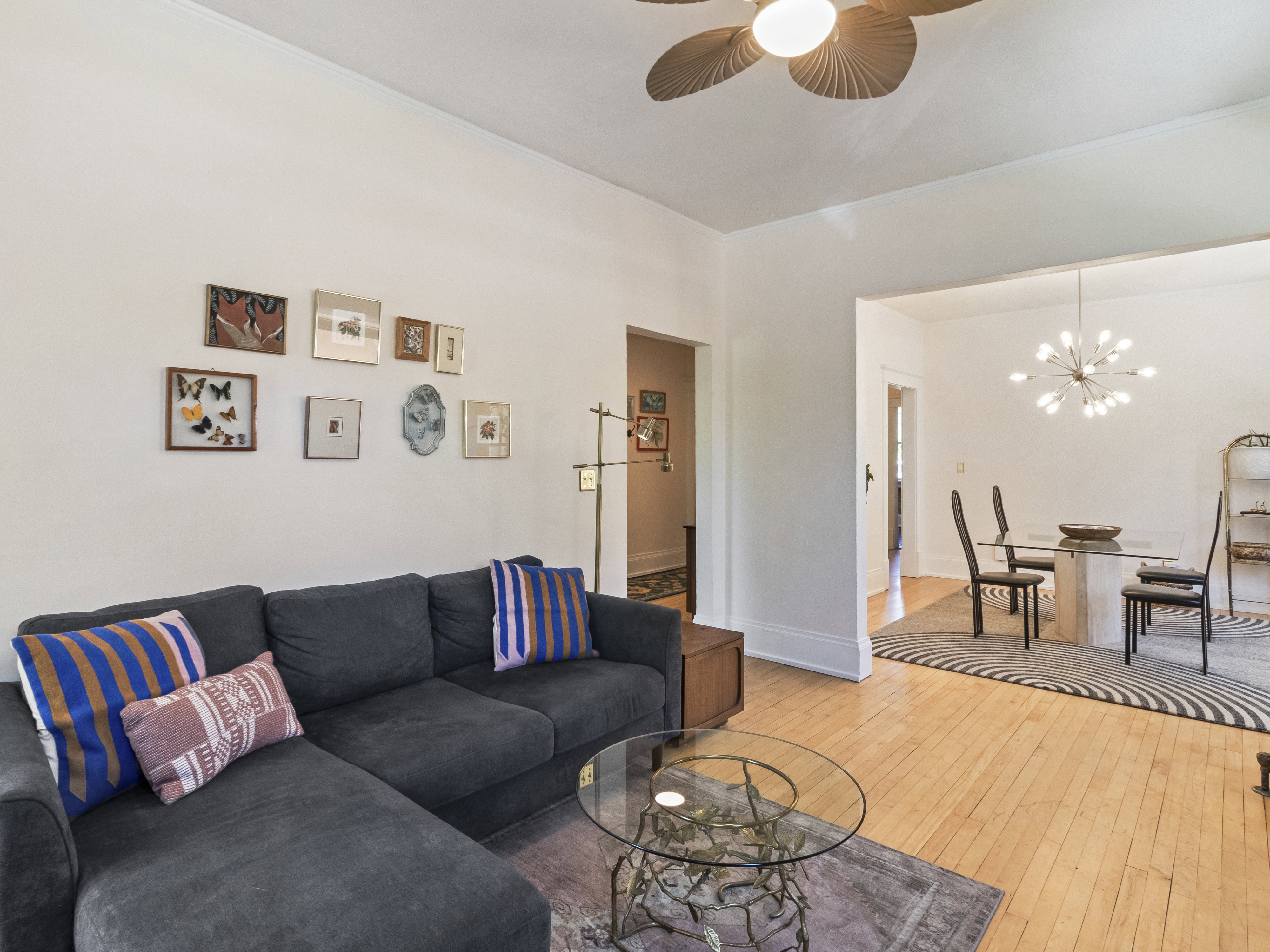 Hardwood flooring extends throughout this living area, featuring a ceiling fan with integrated lighting