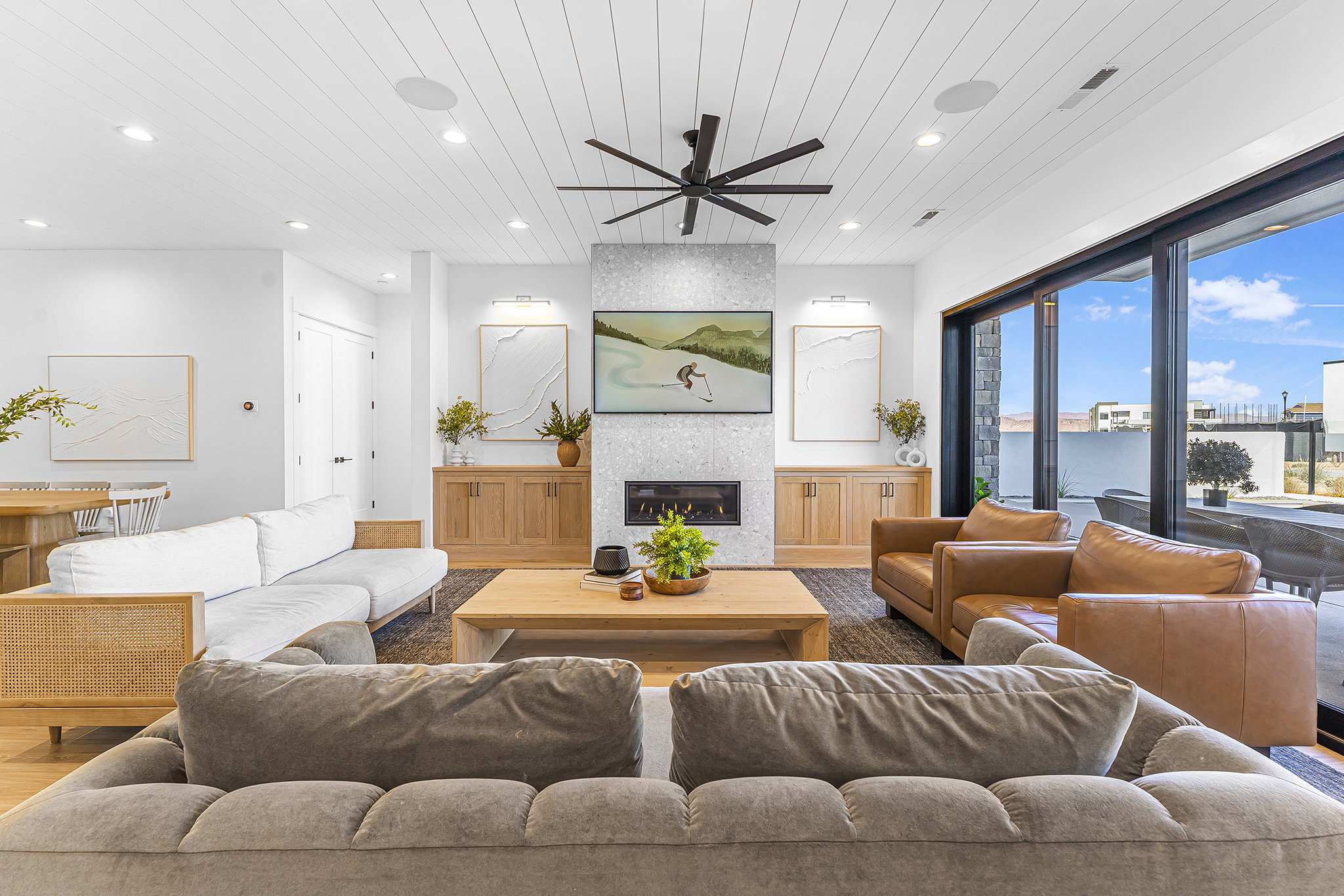 Spacious living area featuring a central fireplace with a textured surround, recessed lighting, and a slatted white ceiling