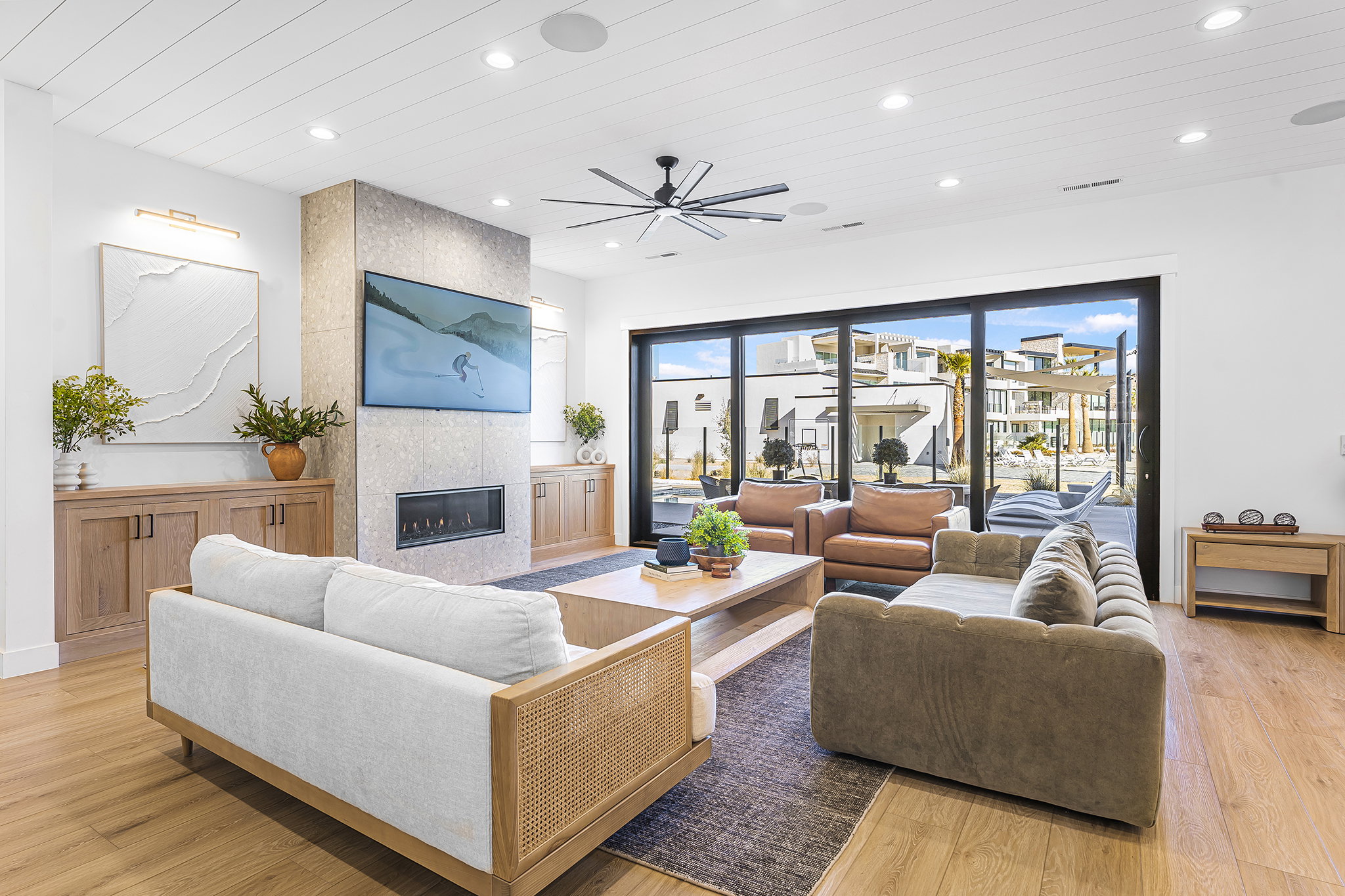 Spacious living area featuring plank wood-finish flooring, a stone-clad fireplace with a mounted television, and built-in cabinetry