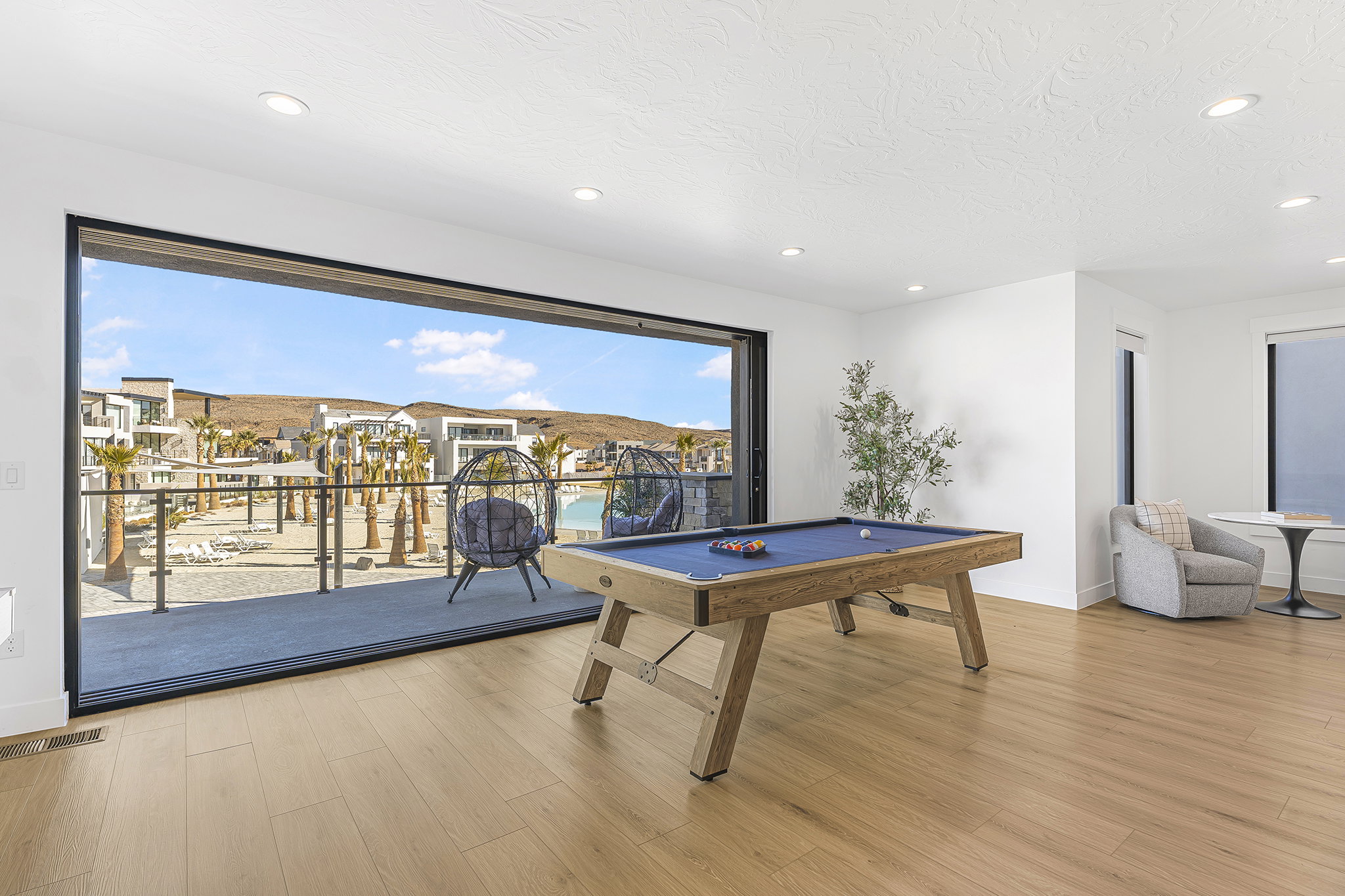 Expansive room featuring a wide sliding glass door, wood-finish flooring, white walls, and recessed lighting