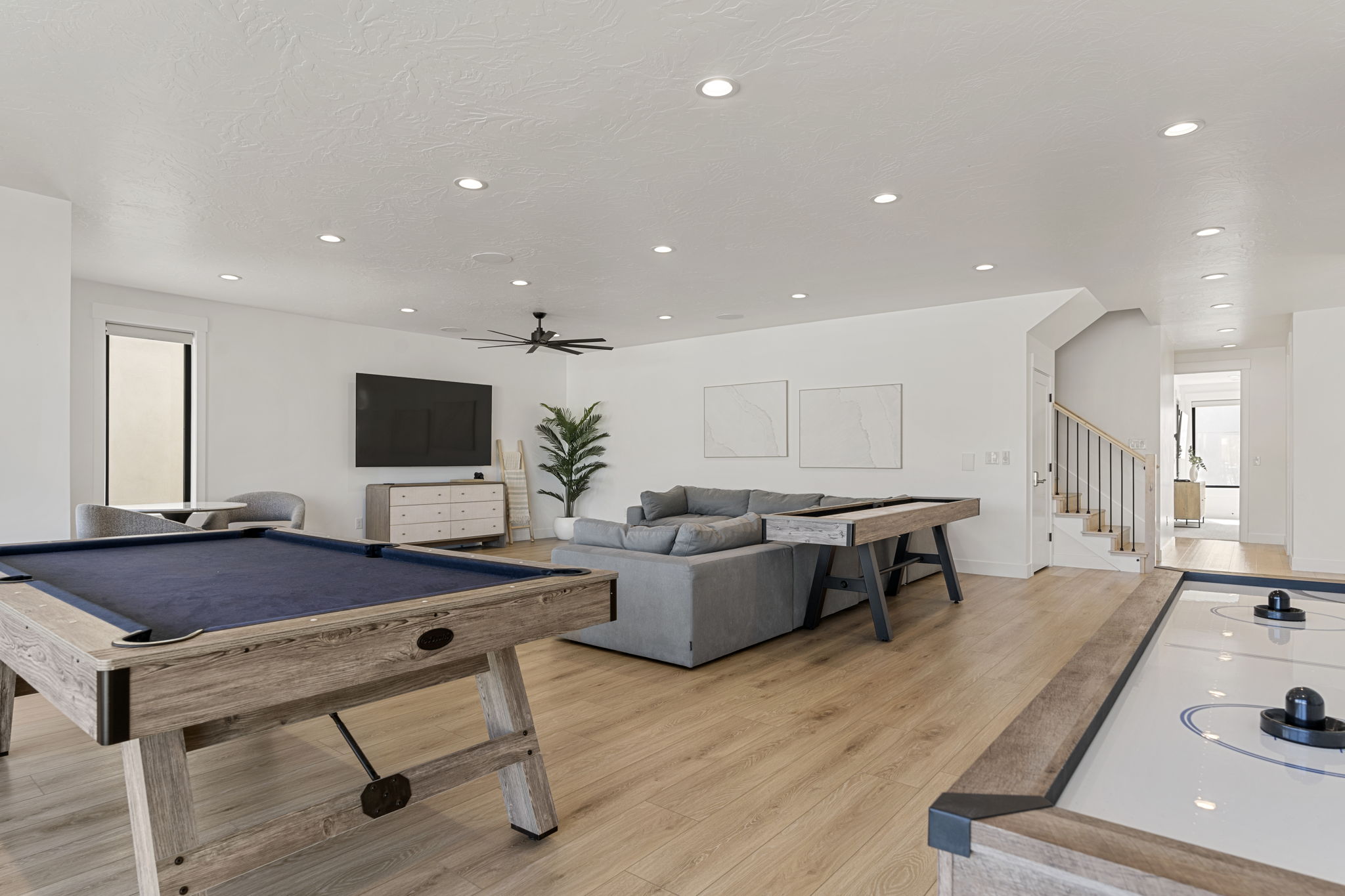 Spacious recreational area featuring wood-finish flooring, recessed lighting, and a modern ceiling fan