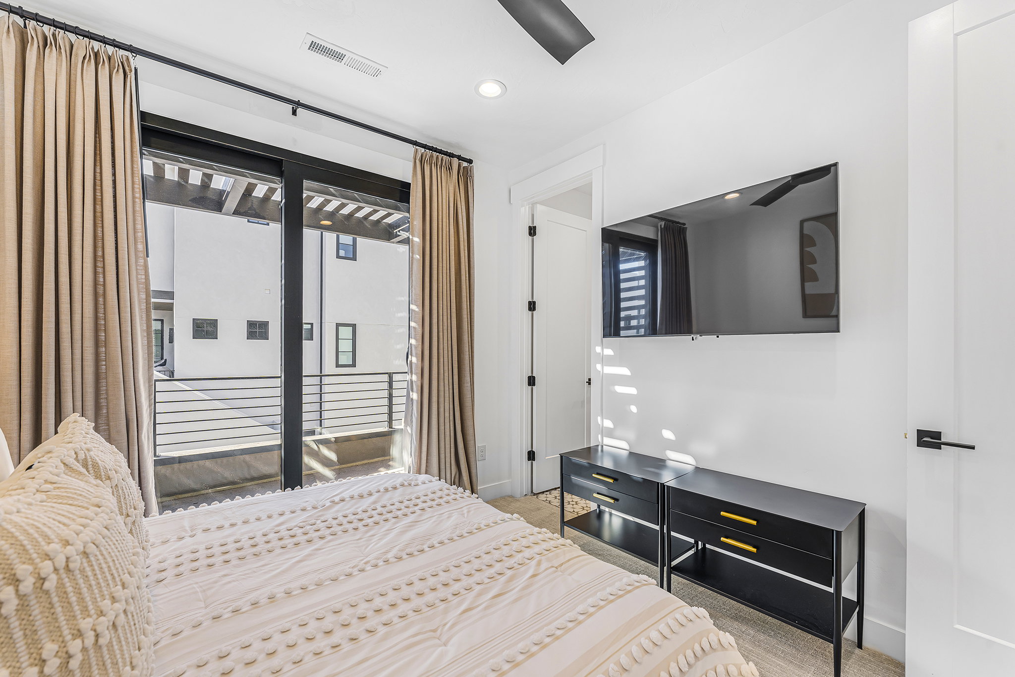 Room featuring a full-light glass sliding door with black framing, leading to an exterior balcony with black metal railings