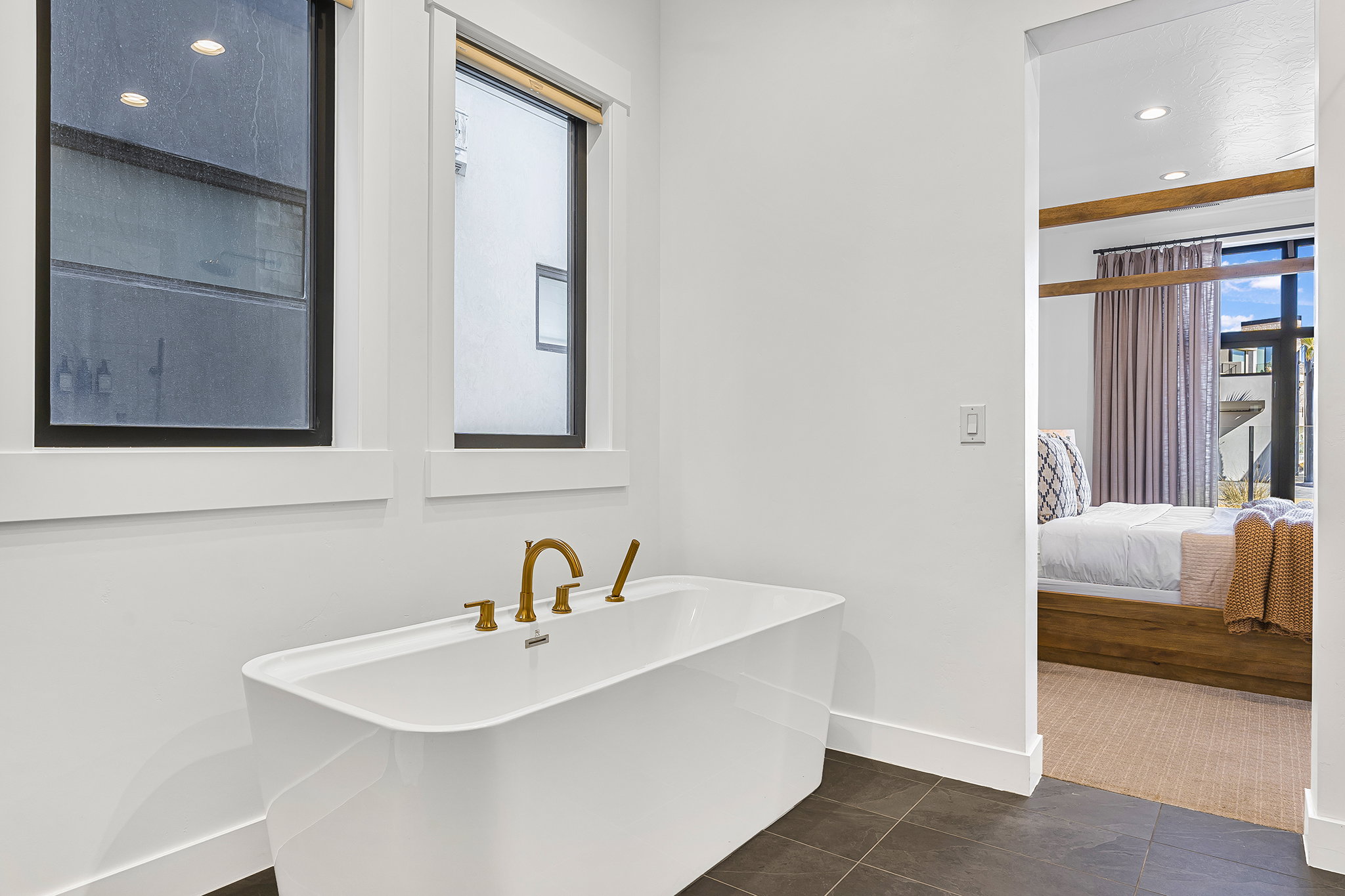 Freestanding bathtub featuring brass fixtures and dual windows