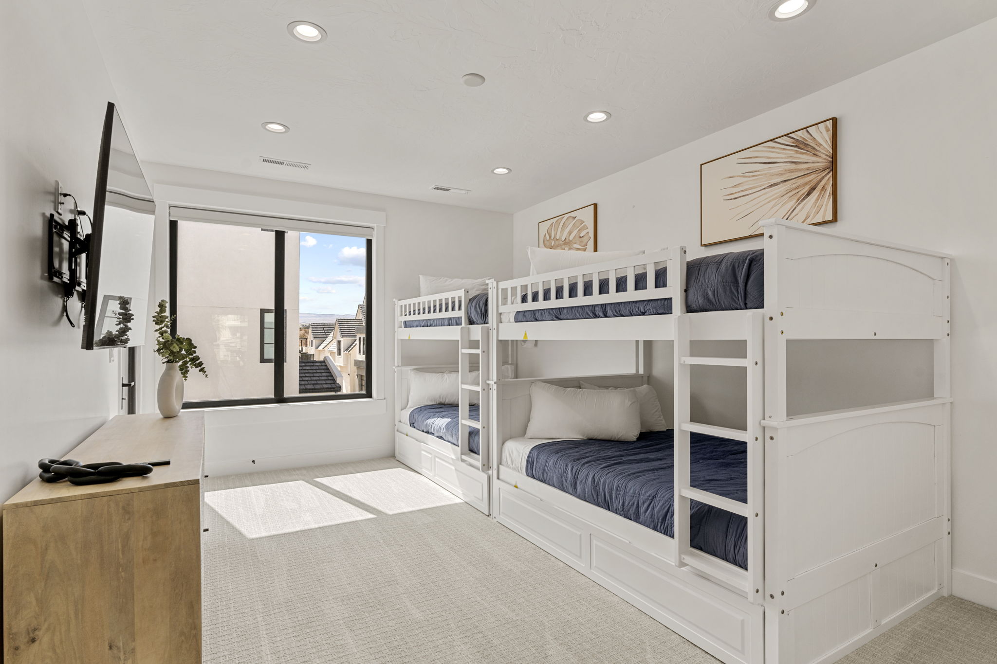 Bright room featuring two white bunk beds with integrated storage drawers