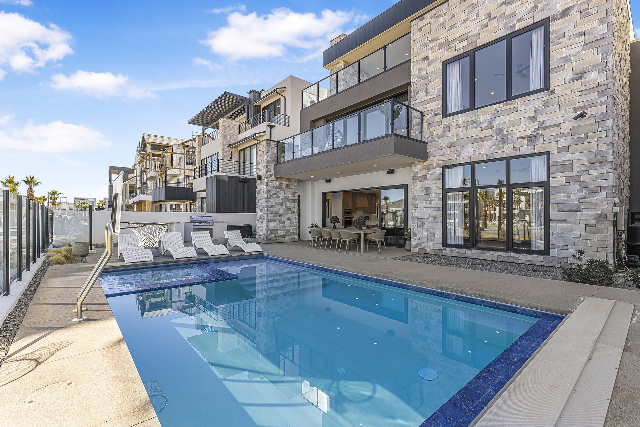 Multi-story residence featuring a stone-clad exterior and multiple balconies with glass railings