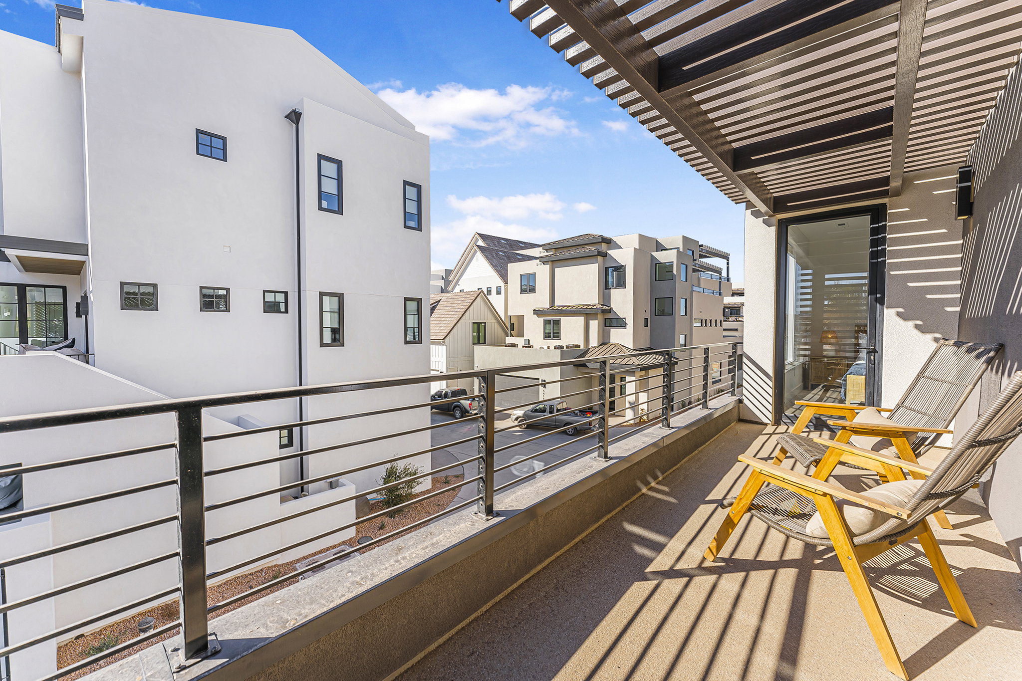 Private balcony featuring a slat-covered pergola, concrete flooring, and metal railings