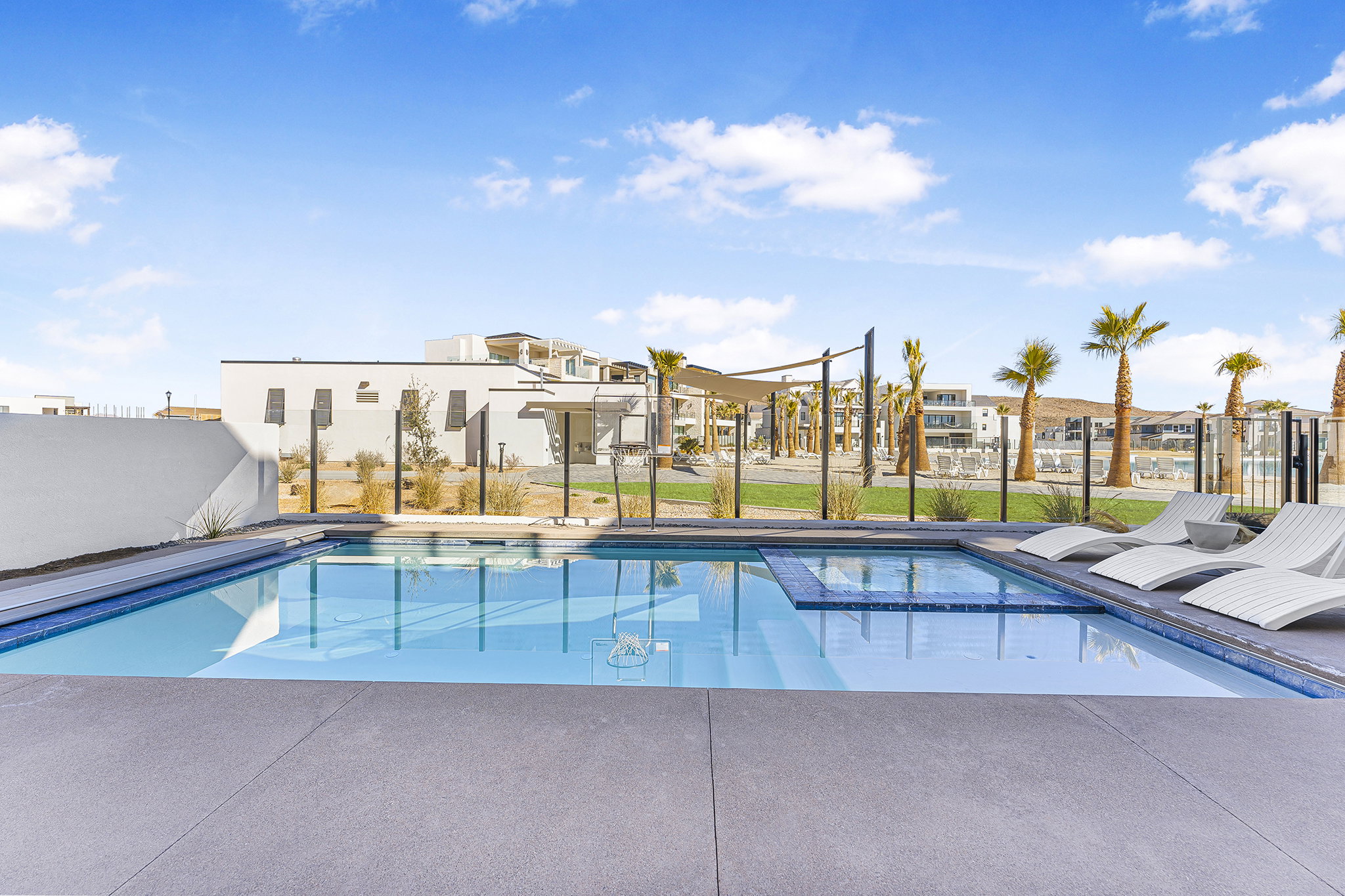 Outdoor swimming pool with integrated spa and surrounding concrete decking