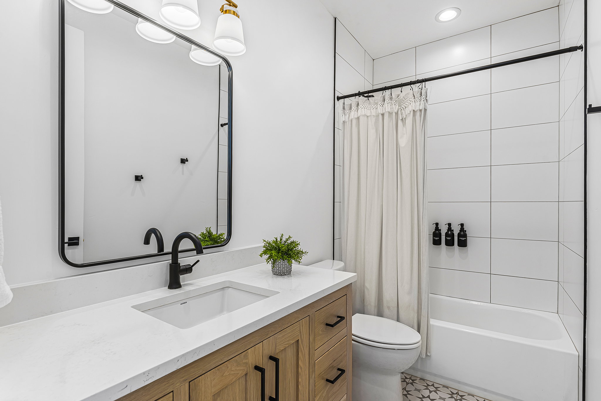 Bathroom featuring a wood-finish vanity with a white countertop and undermount sink, matte black fixtures, and a rectangular mirror
