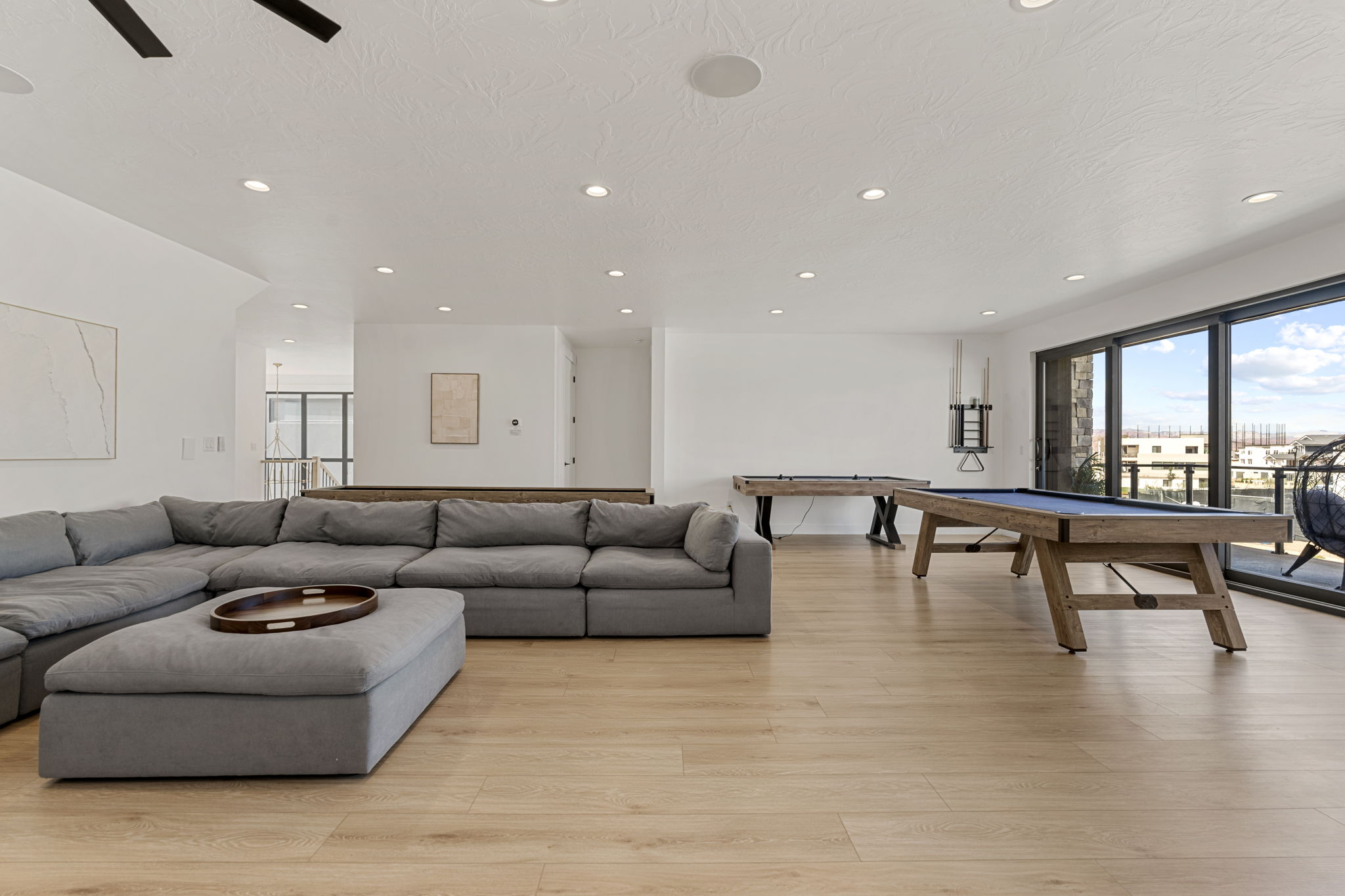 Spacious open-concept room featuring light wood-finish flooring, recessed lighting, and a full wall of sliding glass doors
