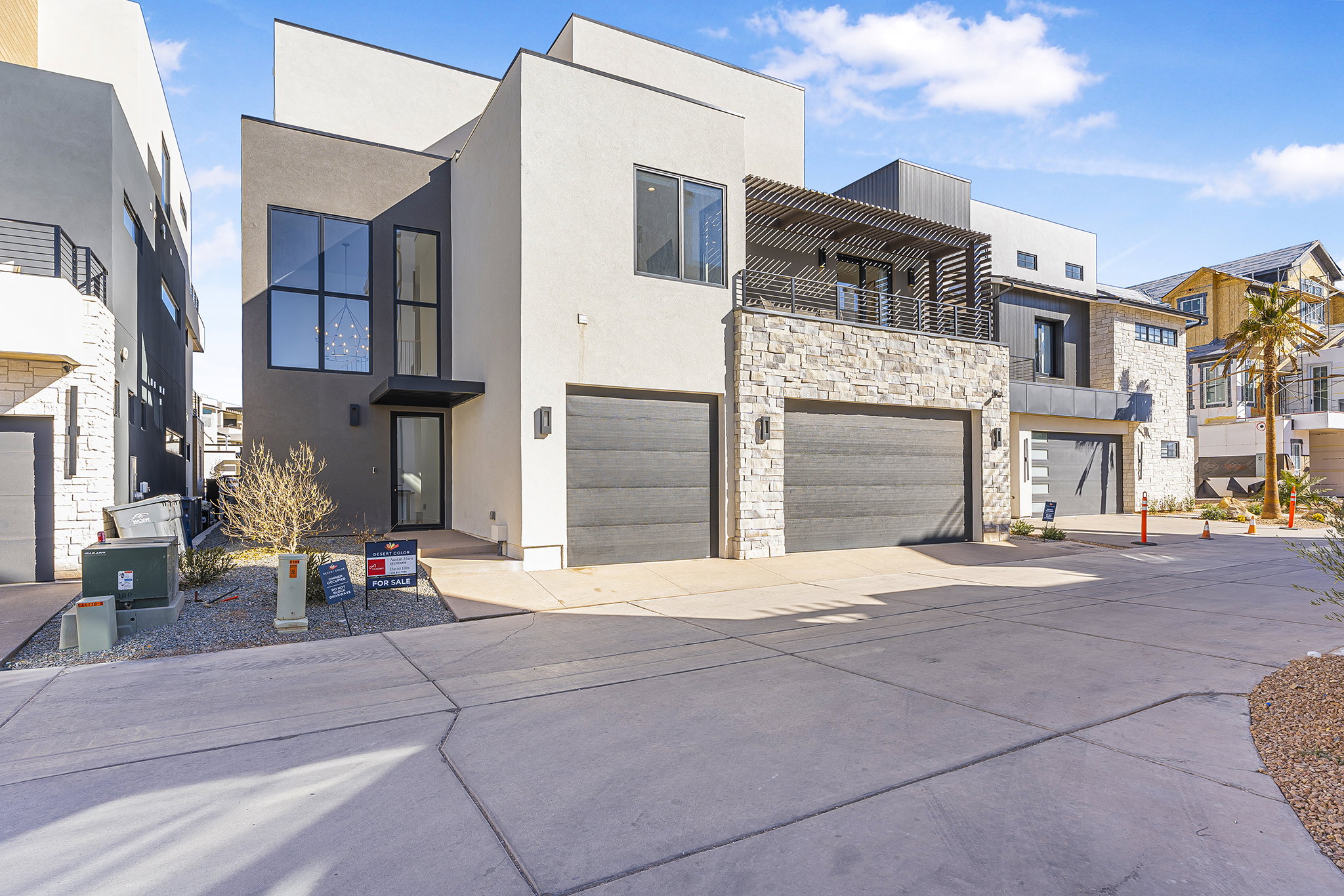 Modern facade featuring clean lines, a stacked stone accent, and dark-paneled garage doors