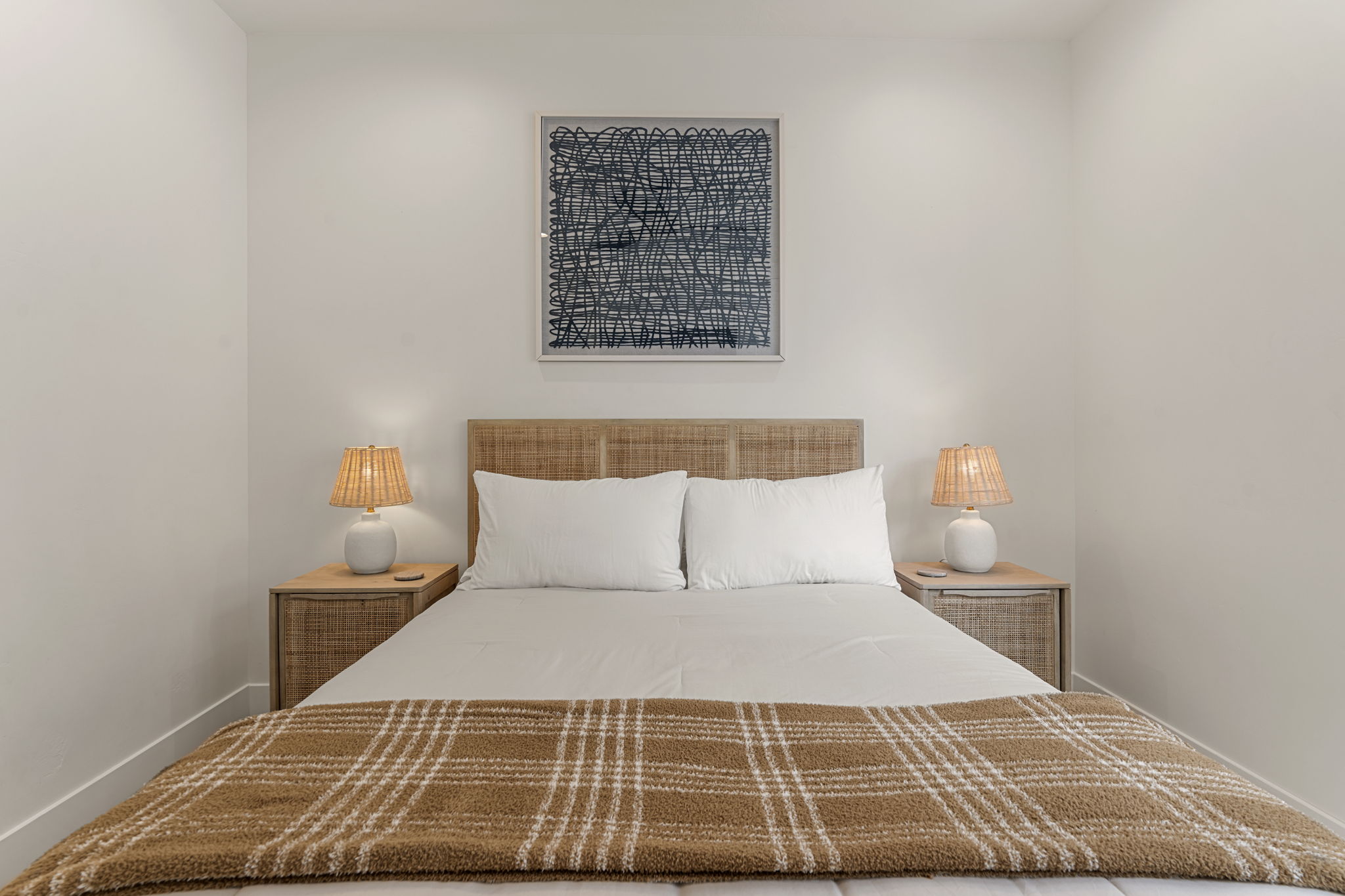 Bedroom featuring a woven headboard, dual integrated nightstands with single drawers, and recessed ceiling lighting