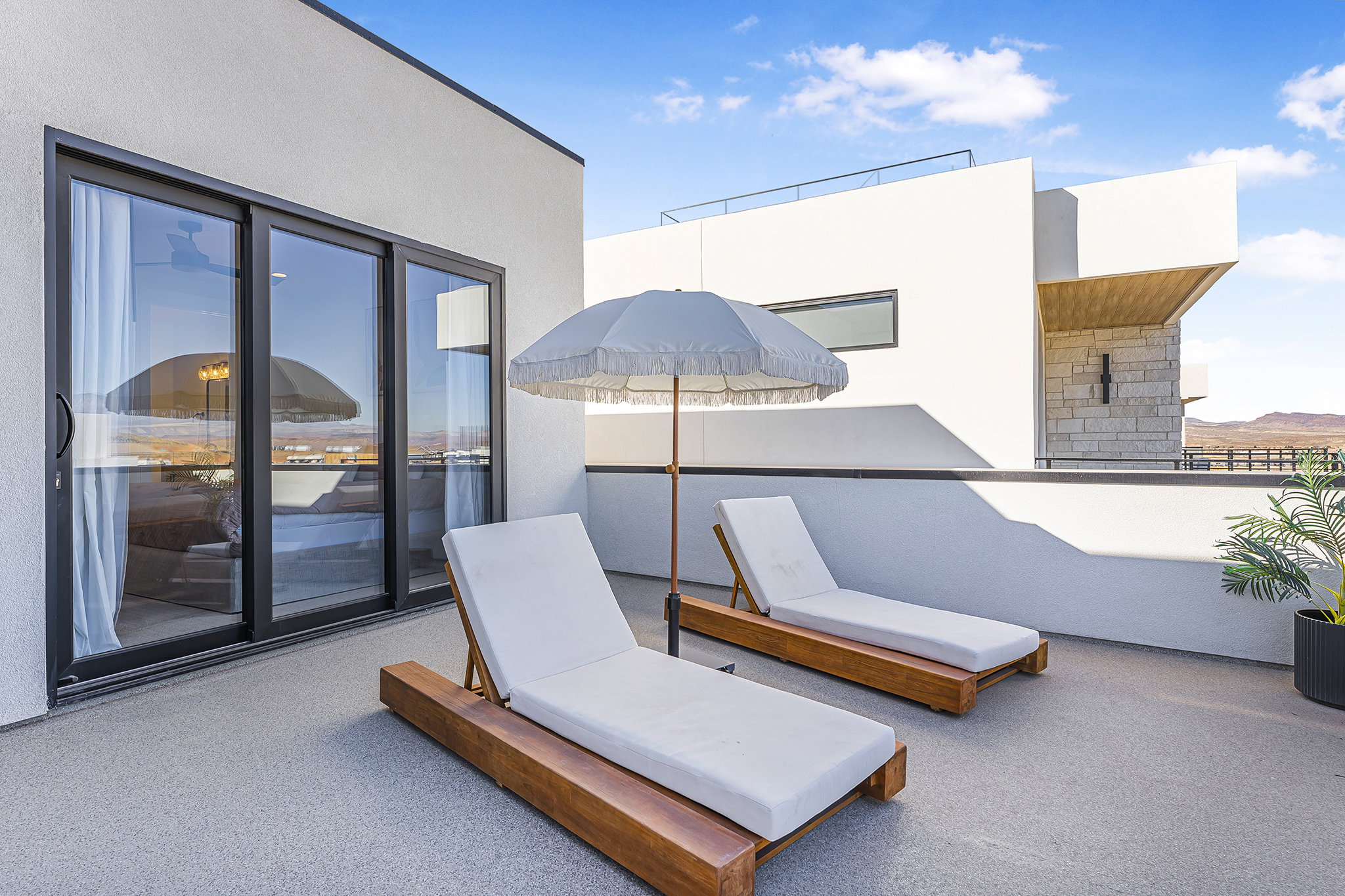 Rooftop deck featuring a light grey textured surface, black-framed sliding glass doors, and a partial privacy wall