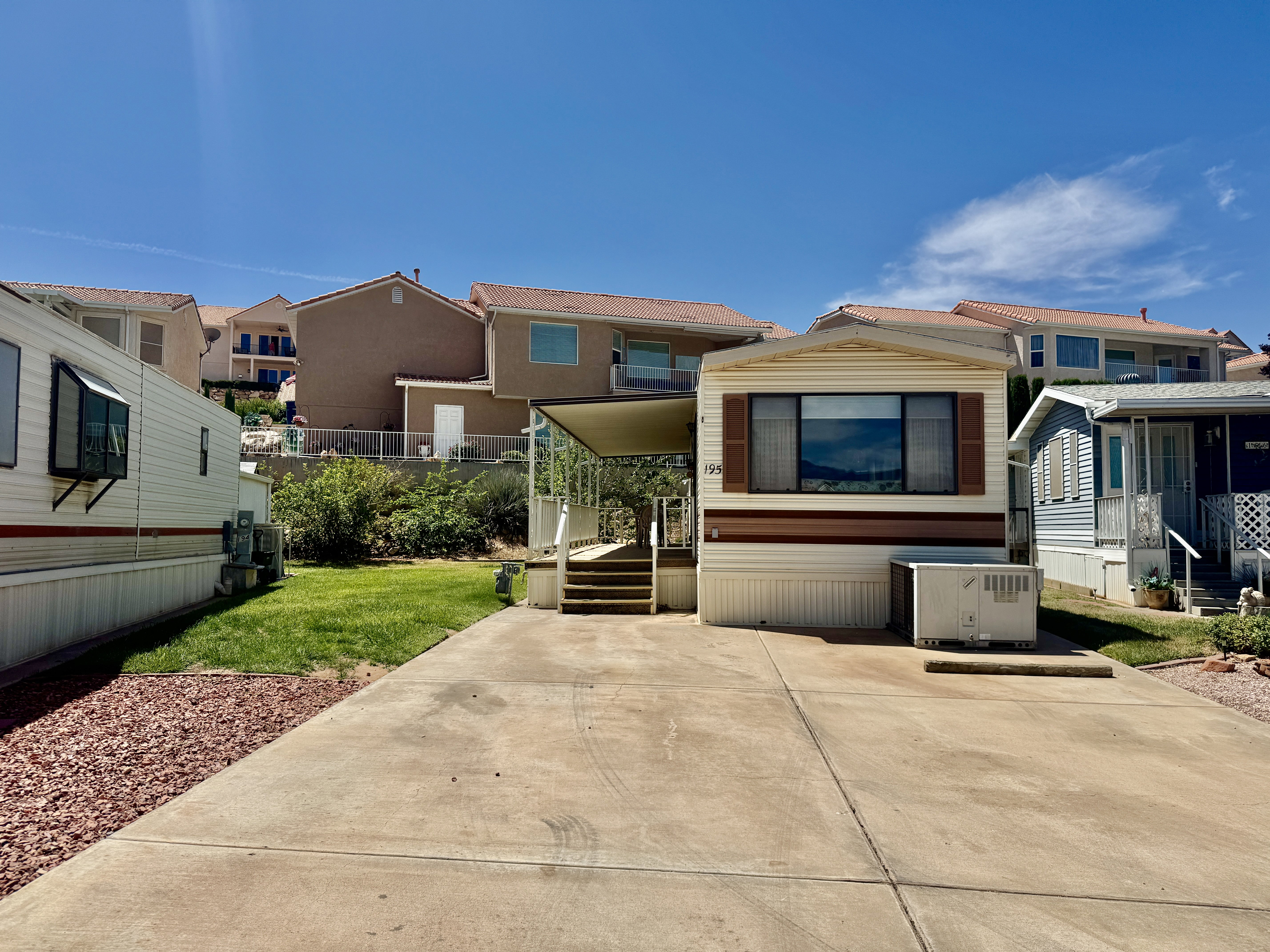 Exterior showcasing a multi-pane window with brown shutters, a covered entry with steps, and a concrete driveway