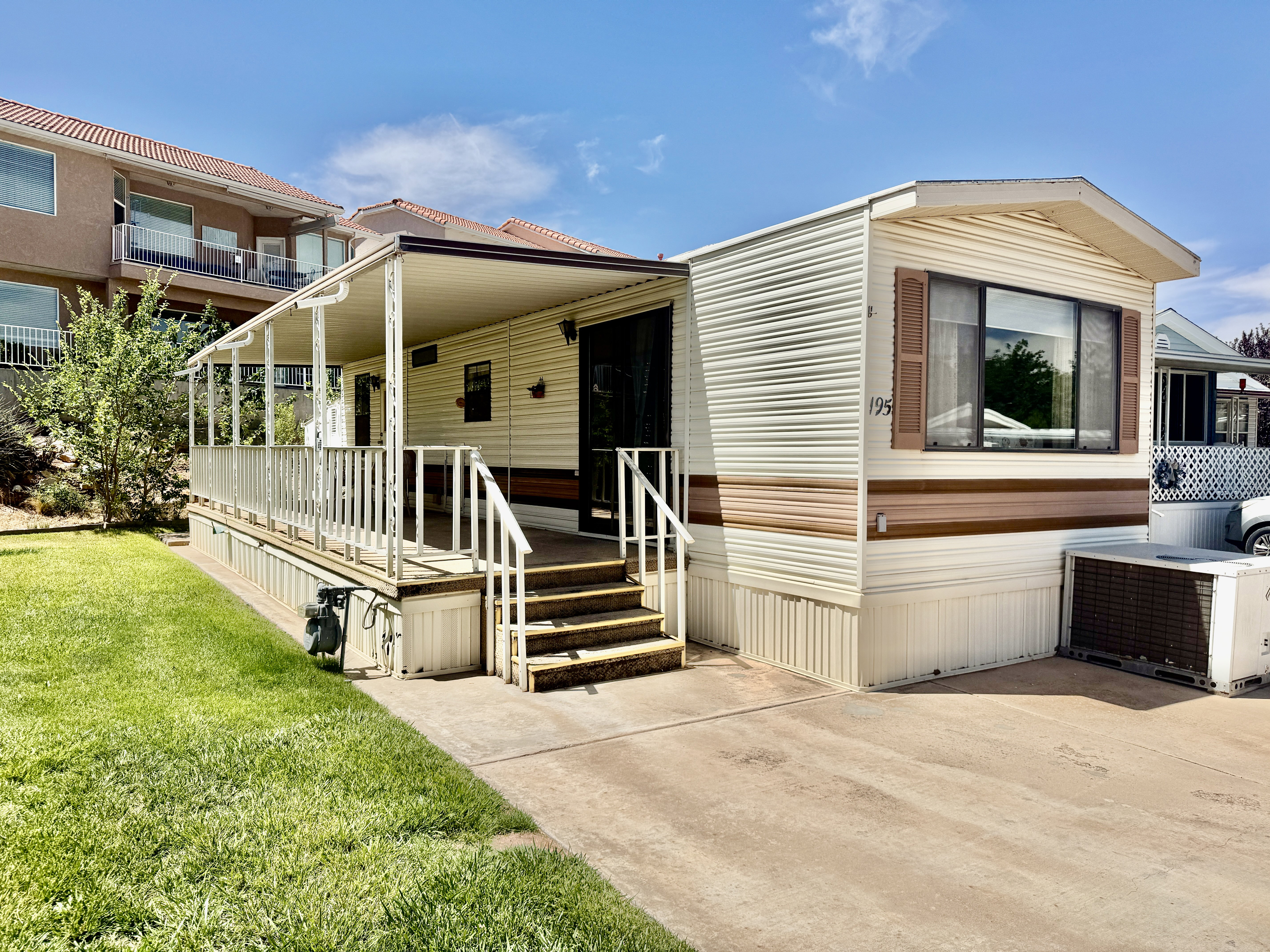 Exterior featuring horizontal siding, an extended covered porch, a concrete driveway, a manicured lawn, and a window with louvered shutters