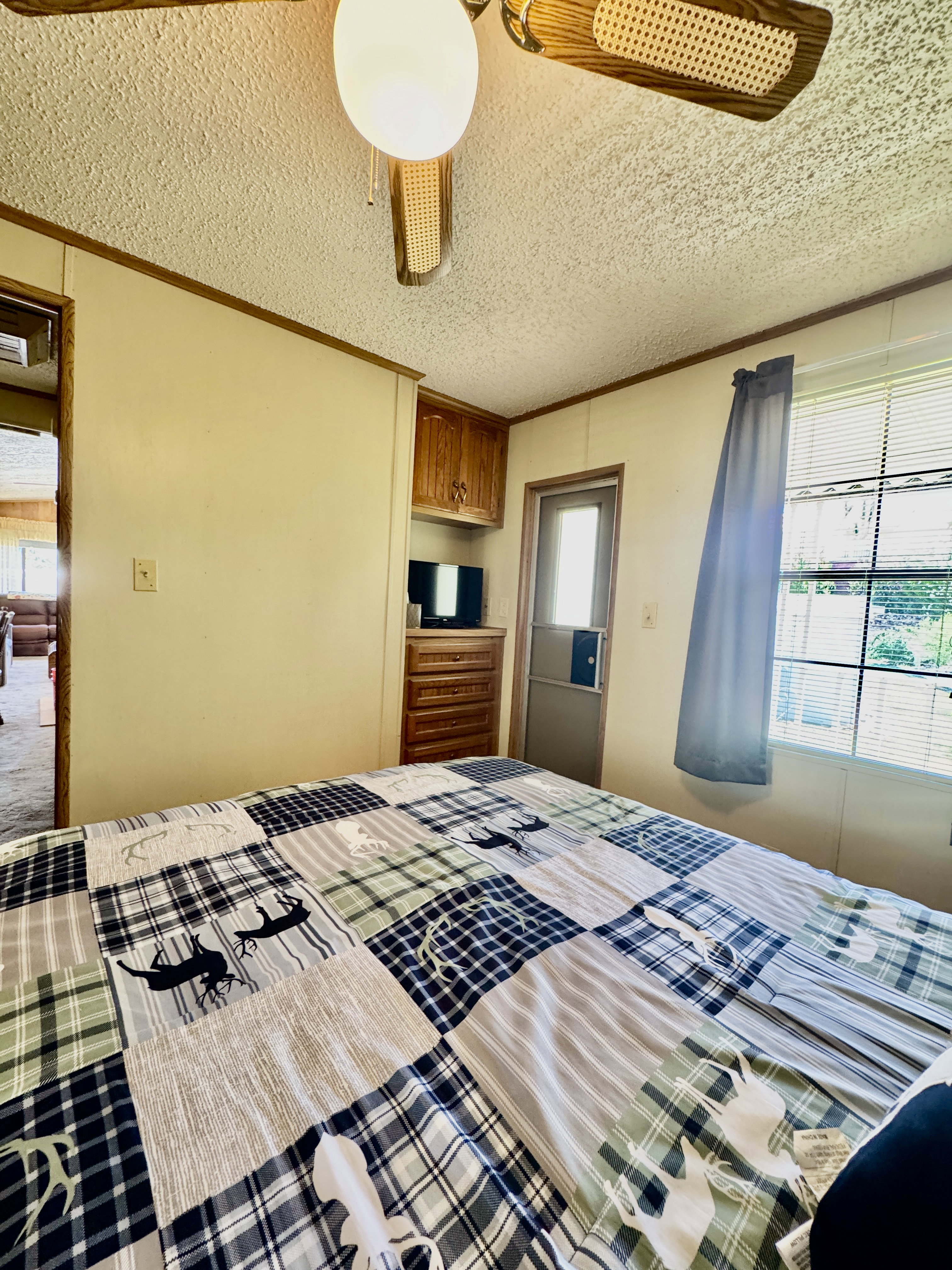 Interior space featuring a ceiling fan with wood-finish blades, a built-in wood-finish cabinet, and a window with blinds
