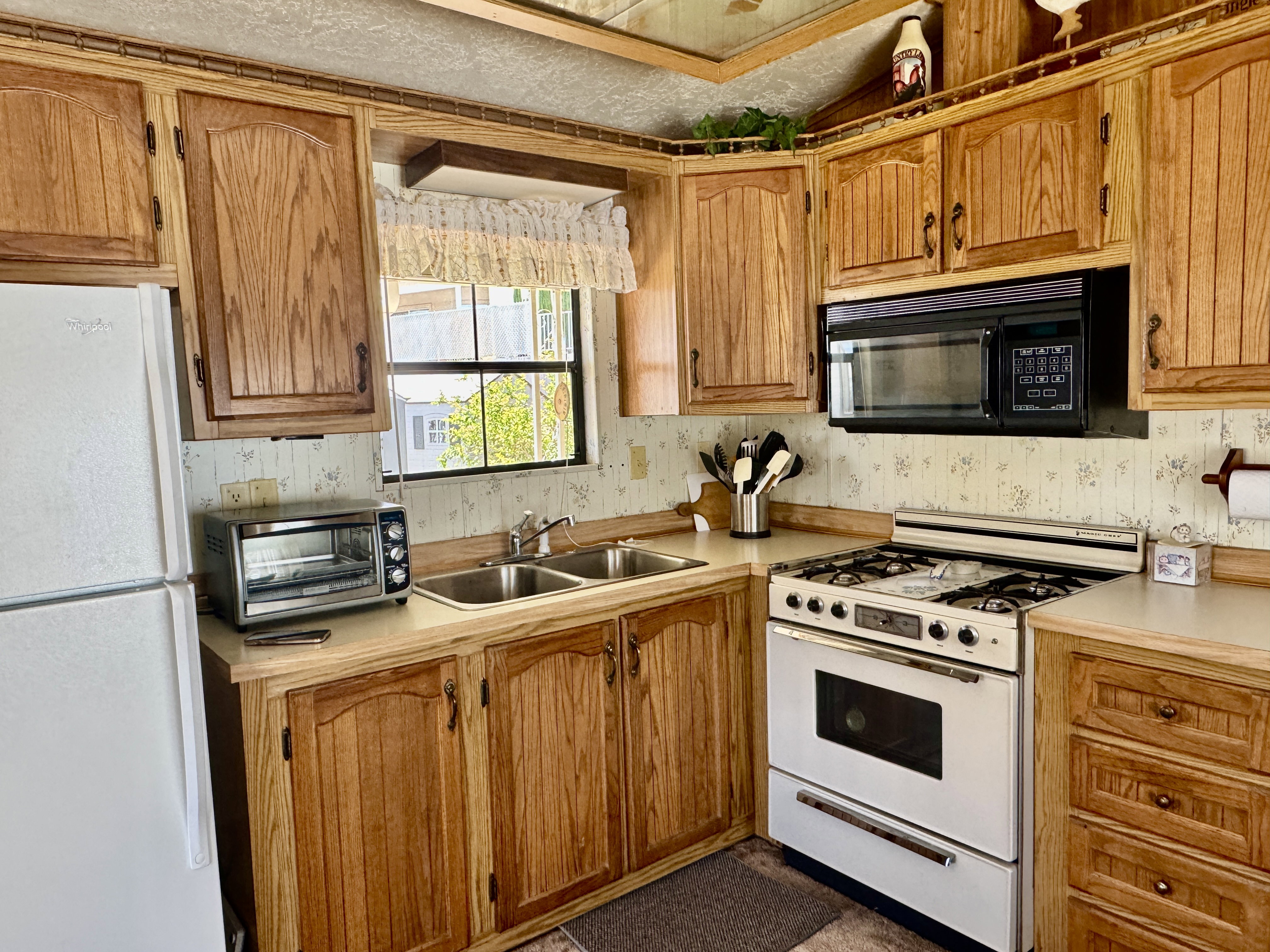 Kitchen featuring wood cabinetry, laminate countertops, double basin sink, and a built-in microwave