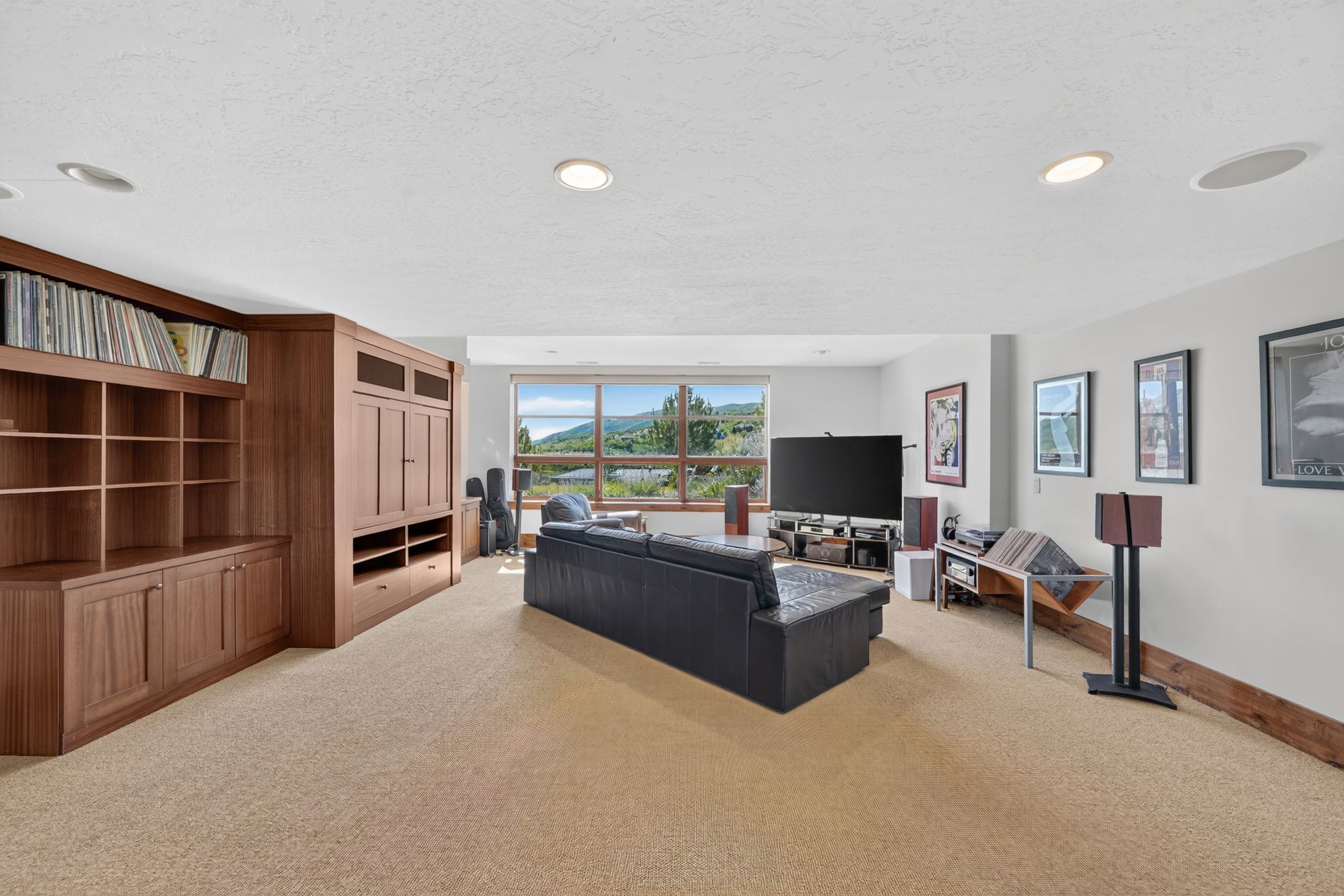 Spacious room featuring extensive built-in cabinetry, recessed lighting, and a panoramic window showcasing distant mountains