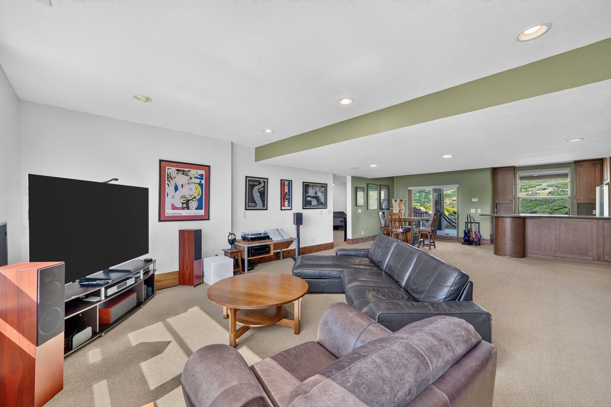 Spacious room featuring neutral carpeting, a built-in wet bar with wood cabinetry, recessed lighting, and a sliding glass door leading to an outdoor area