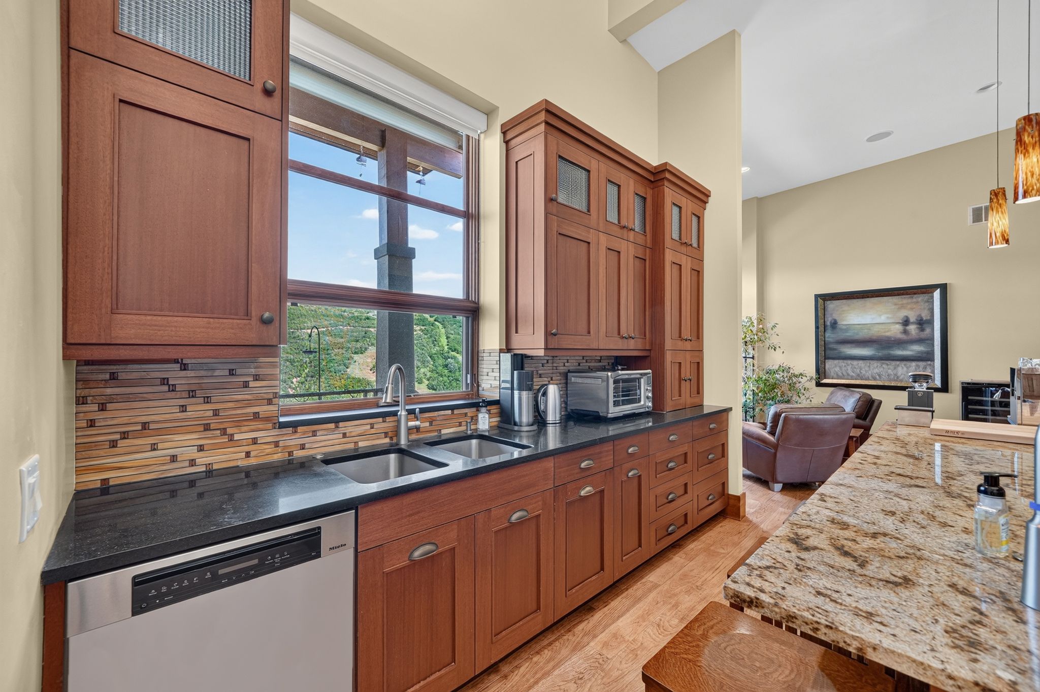 Kitchenette featuring cherry wood cabinetry, a stainless steel double sink, and a black countertop