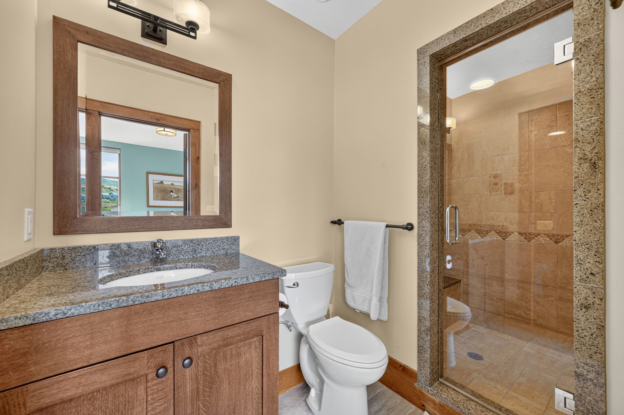 Bathroom featuring a wood-finish vanity with an undermount sink and stone countertop