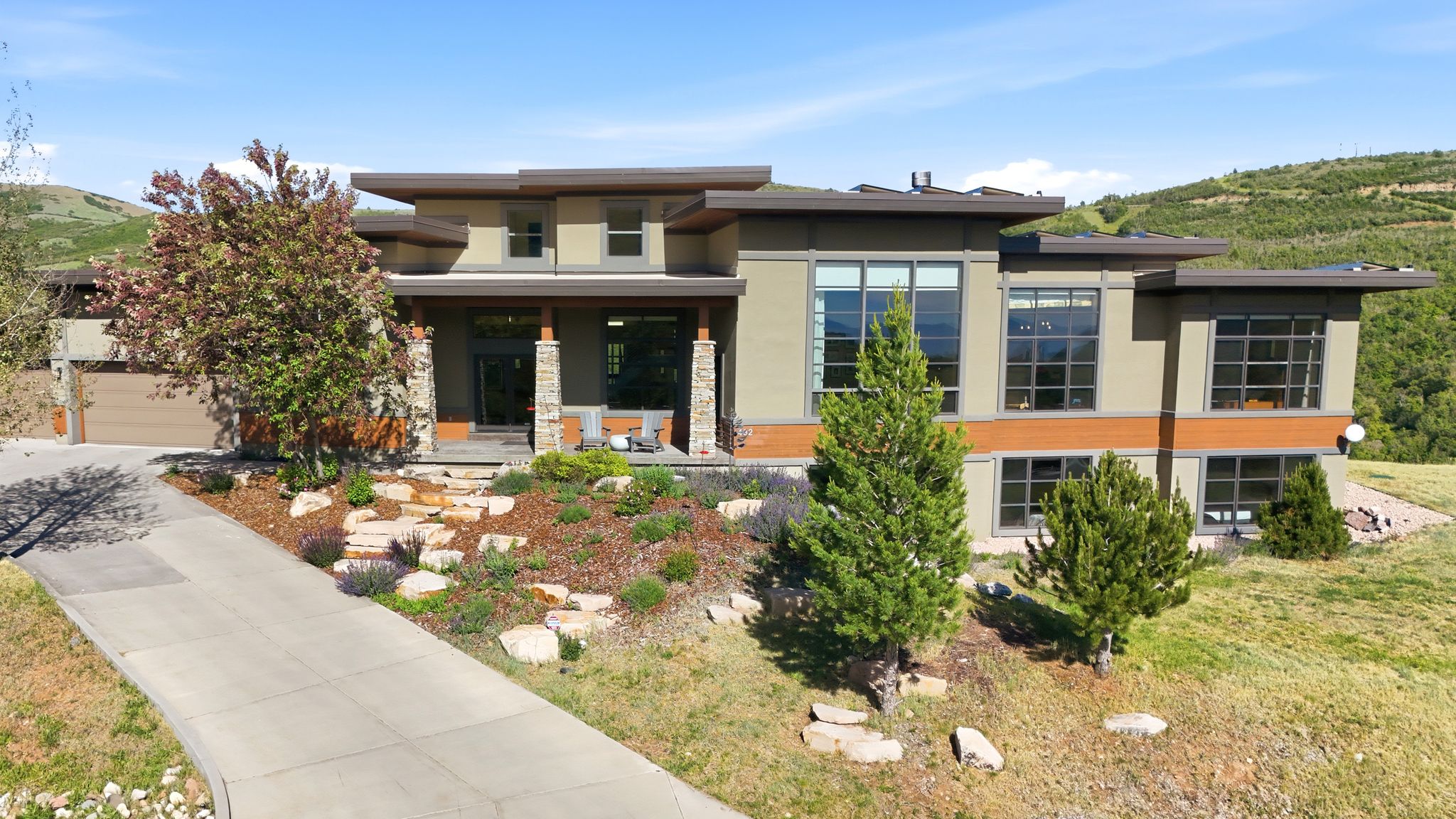 Modern architectural exterior featuring multiple large windows, stone column accents, and a multi-level design
