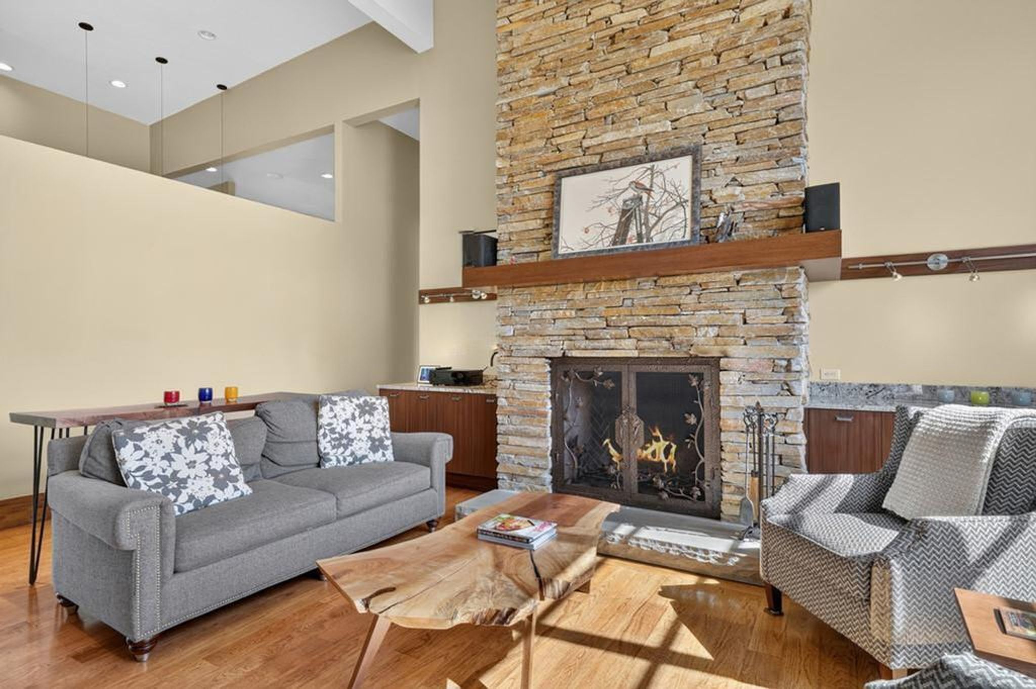Stacked stone fireplace with a decorative metal screen, complemented by a wood mantel
