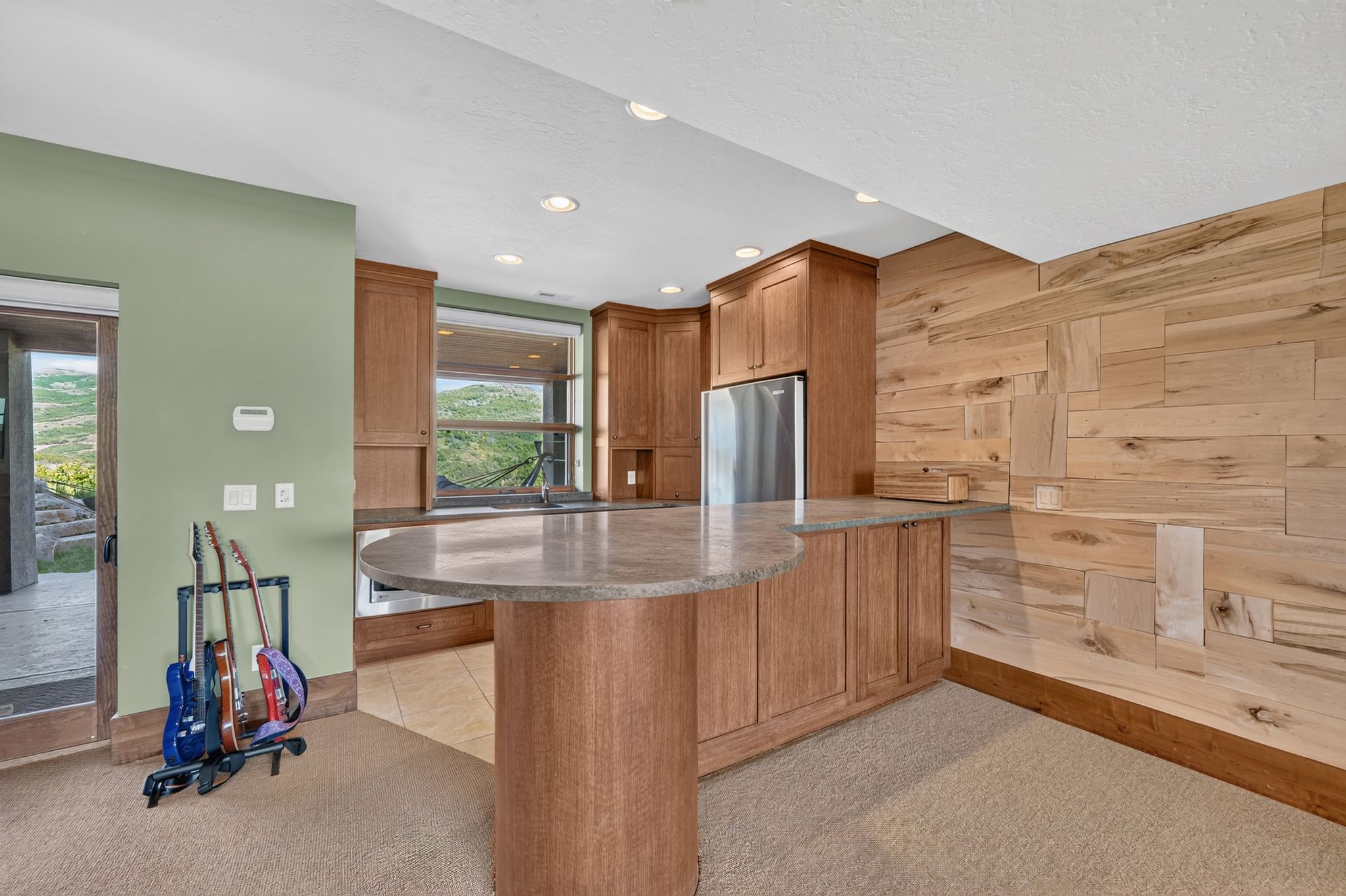 Built-in bar area featuring wood cabinetry, stainless steel refrigerator, and a stone-finish countertop