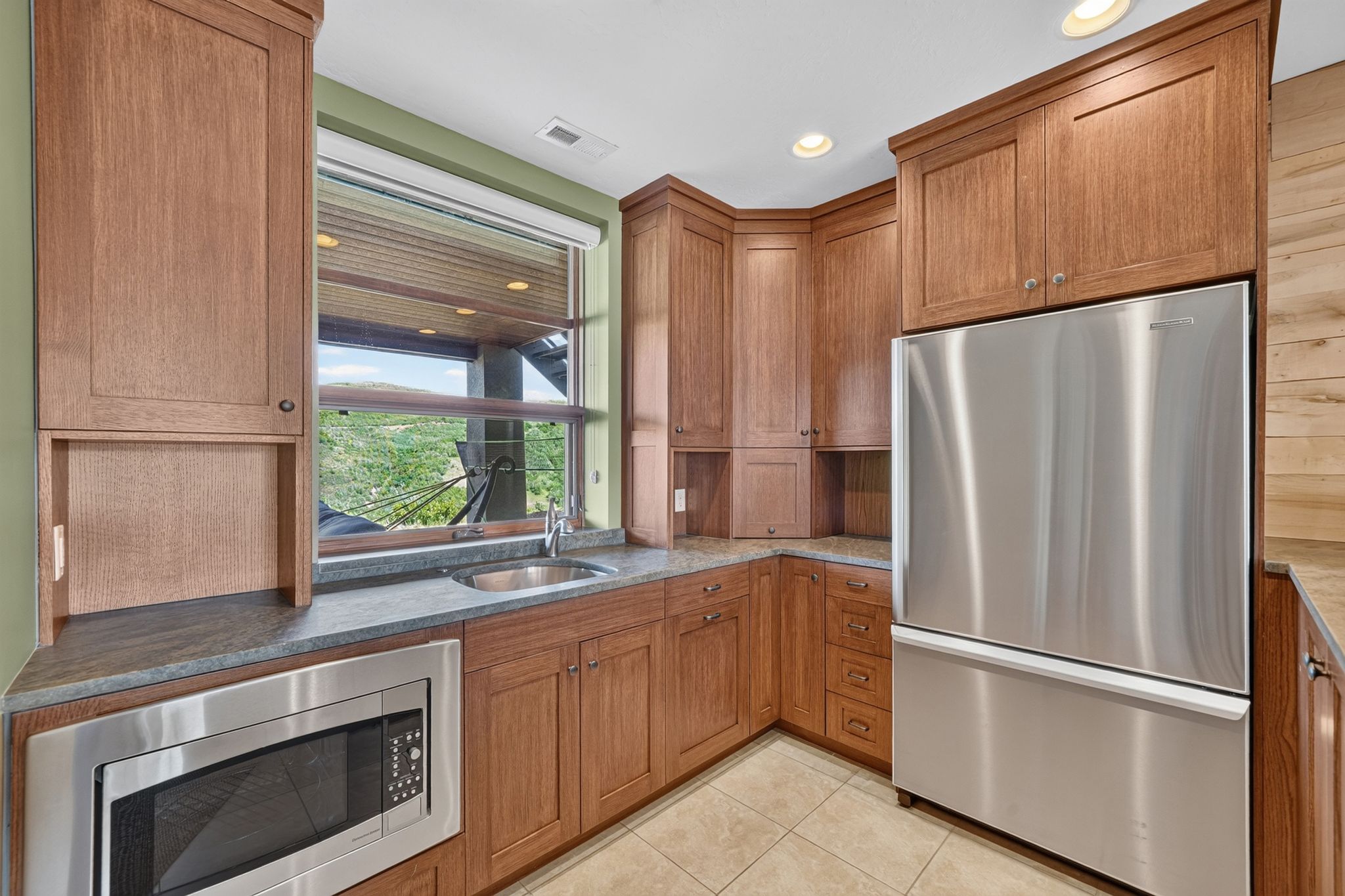 Wood-finish cabinetry paired with stainless steel appliances, including a microwave and refrigerator