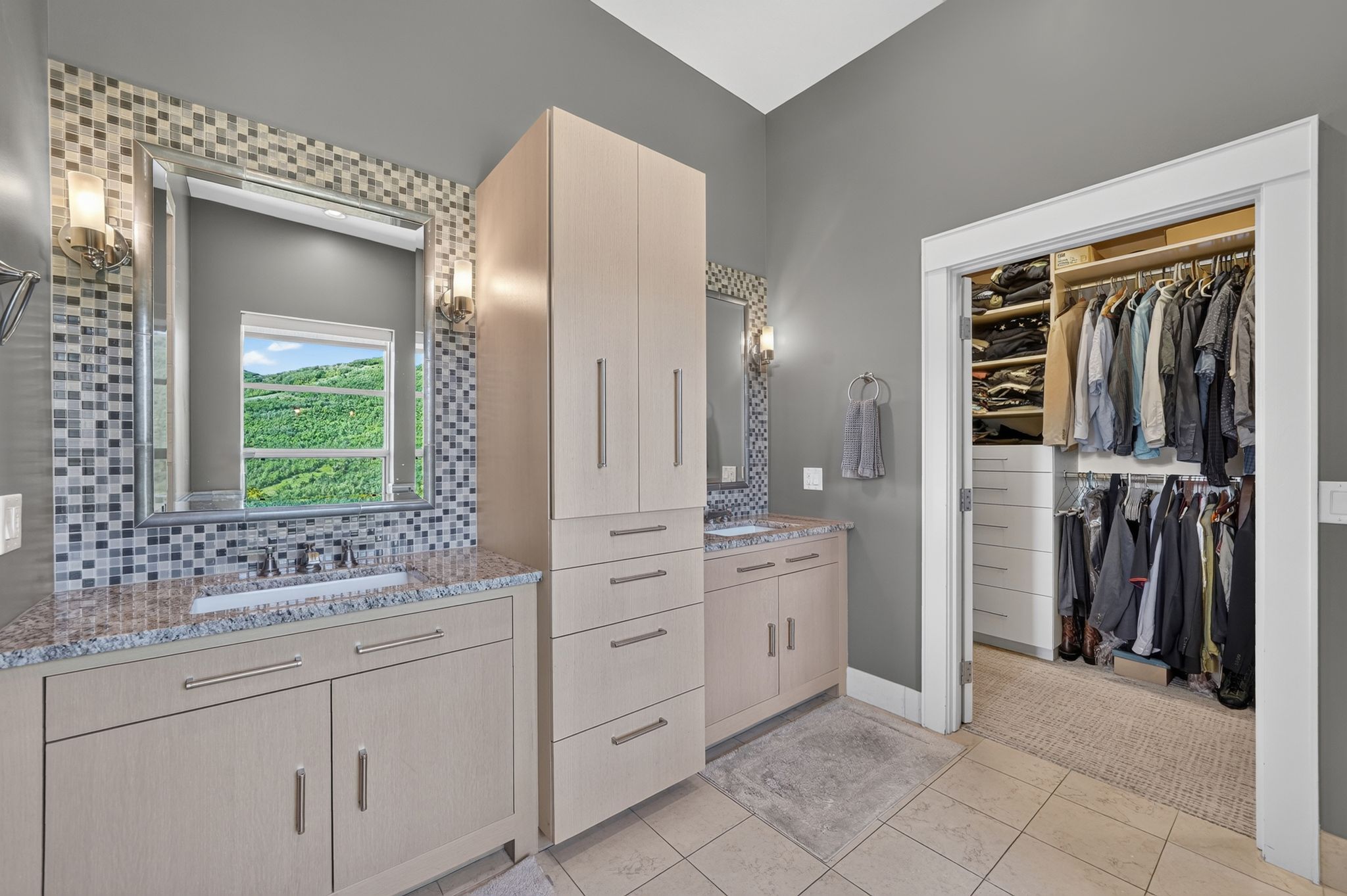 Dual vanity with granite countertops, mosaic tile backsplash, and individual sconce lighting