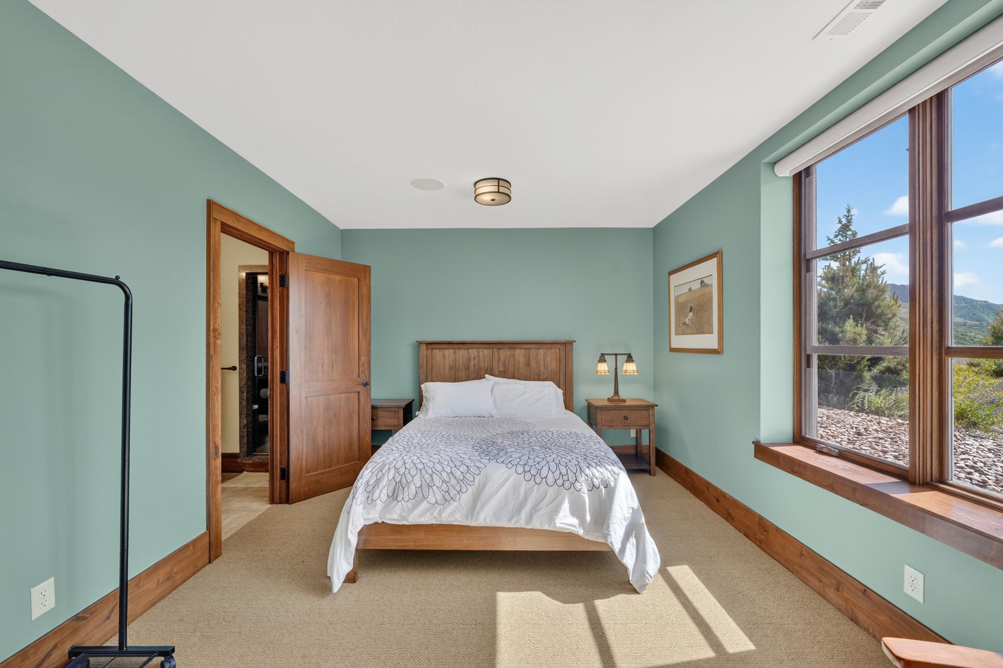 Spacious room featuring a large window, earth-toned carpeting, wood-finish trim, and a prominent wood-finish door