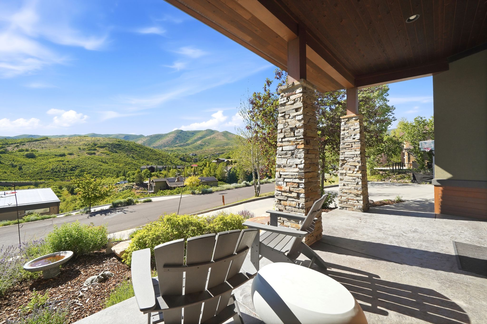 Covered front porch featuring stacked stone columns, a wood-paneled ceiling, and a concrete patio