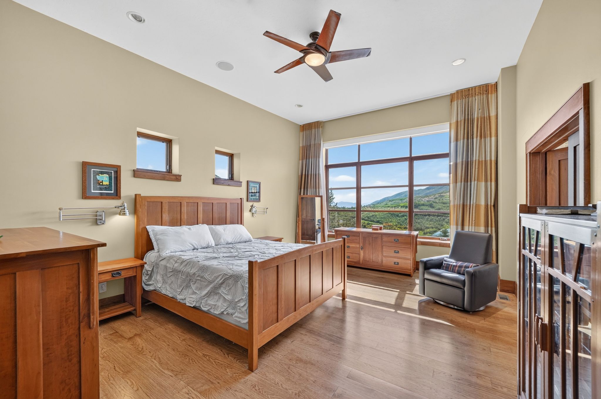 Room with hardwood flooring, a large picture window, recessed lighting, a ceiling fan, and multiple smaller windows