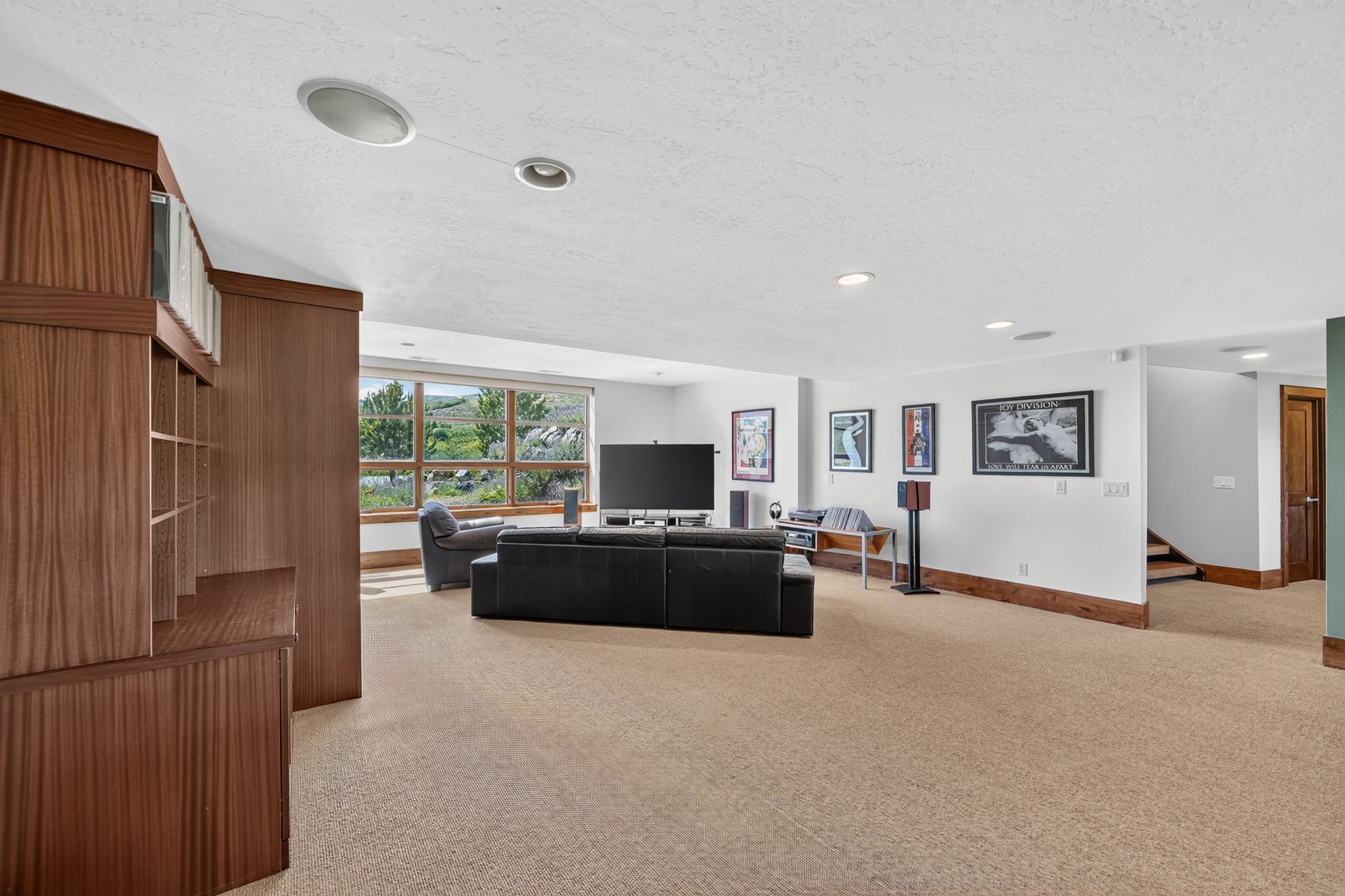 Expansive room featuring warm wood-finish built-in cabinetry, recessed lighting, and a broad bank of windows